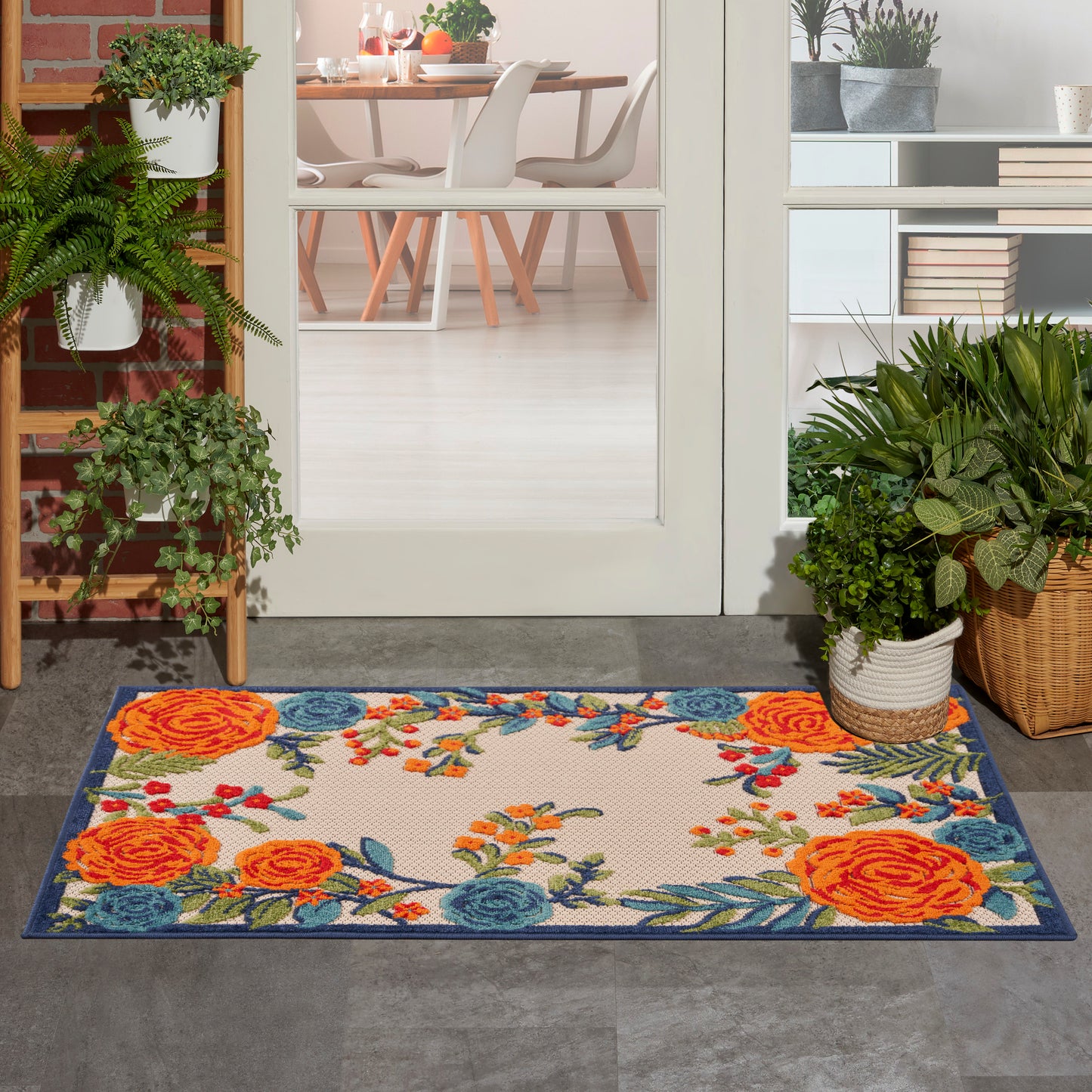 Floral area rug with vivid orange and blue flowers, beige center and navy border, suitable for an entryway.