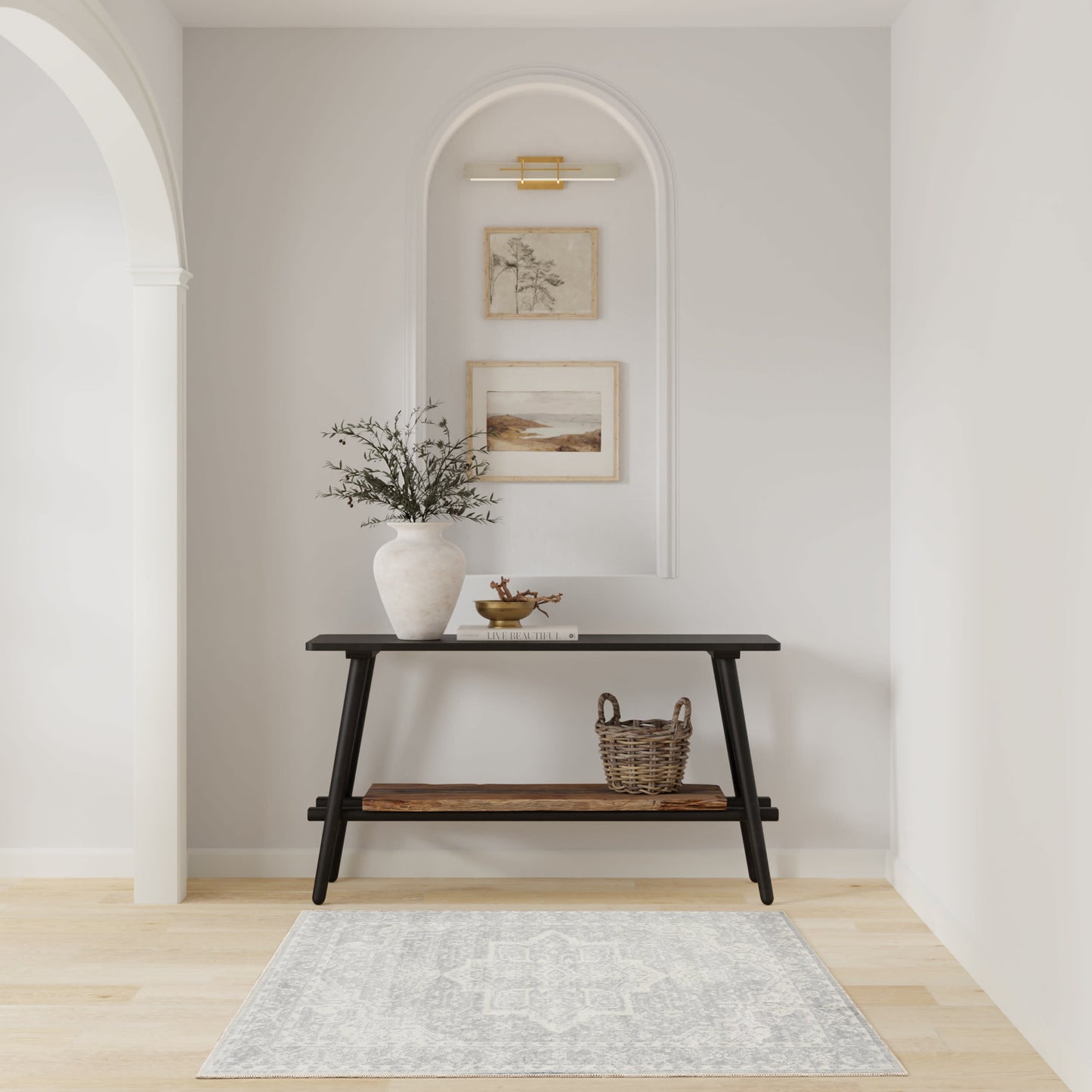 Black two-tier mid-century console in an arched alcove with greenery vase, framed art, basket, and gray patterned rug.