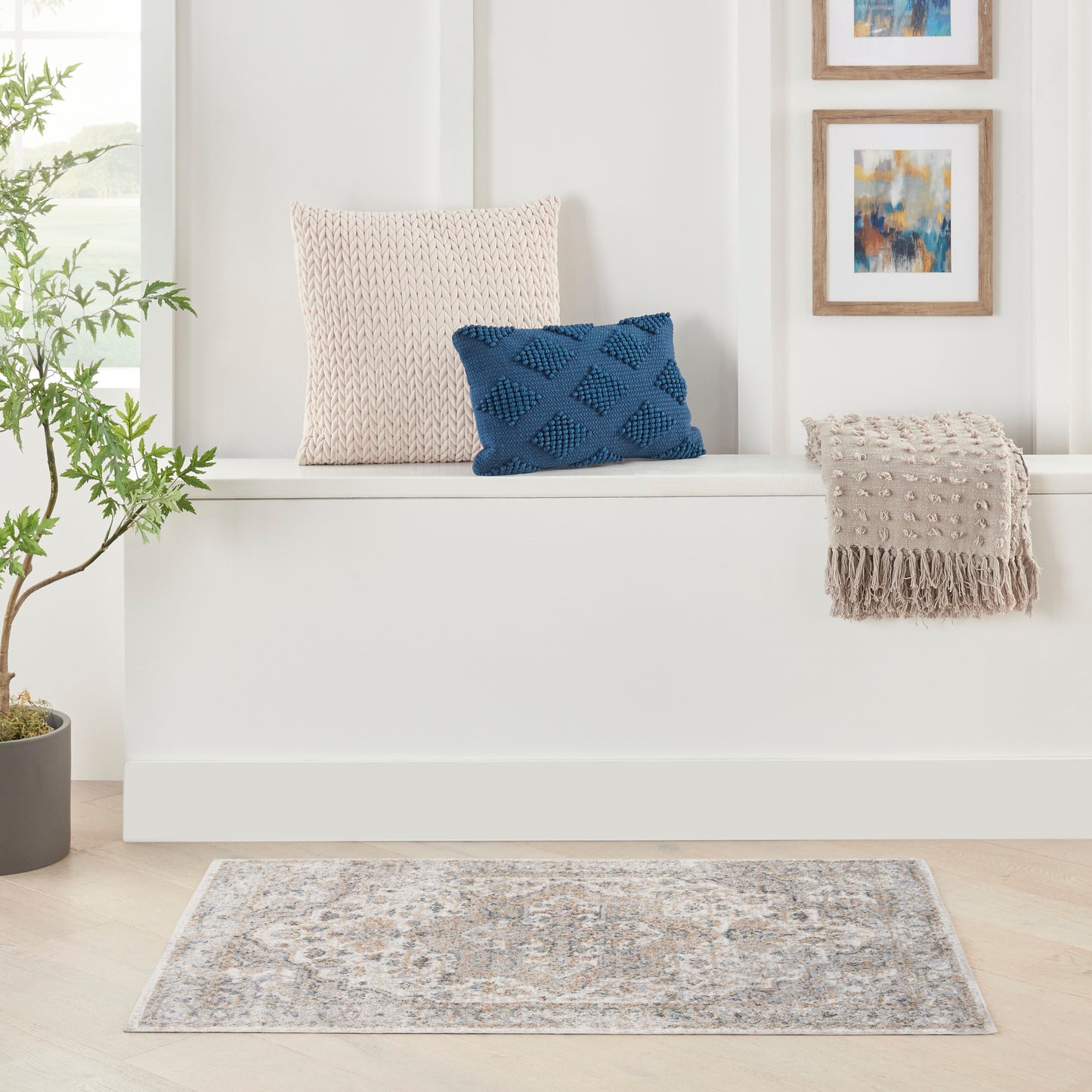 Soft grey-blue patterned area rug on light wood floor with beige knit pillow and blue textured pillow.