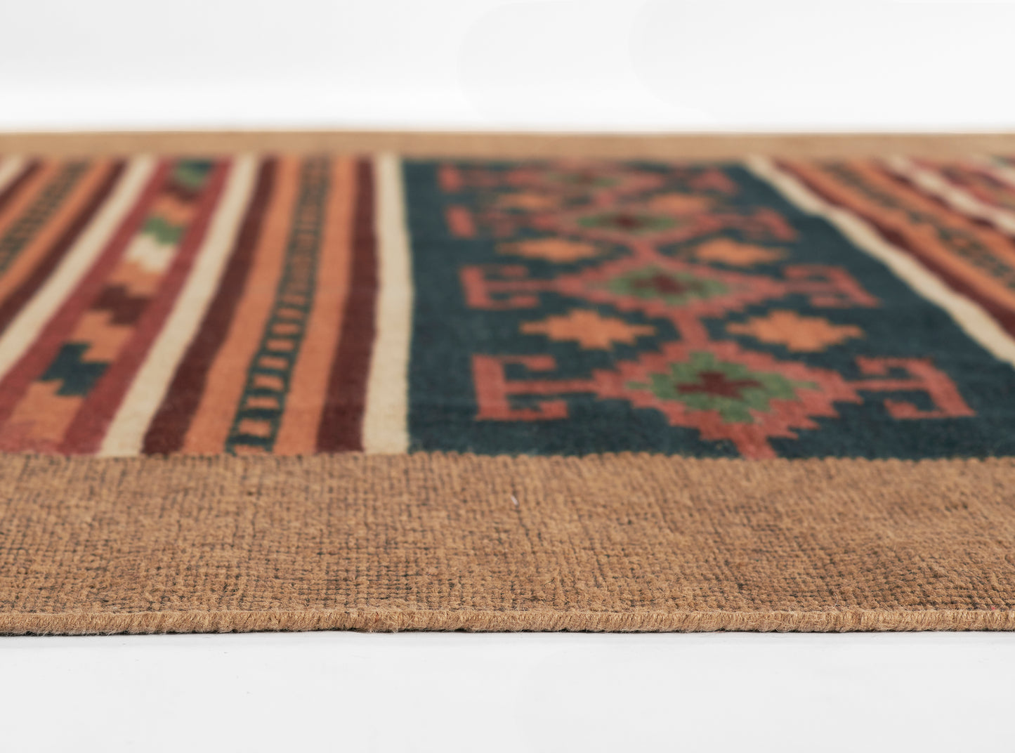 Close-up of a woven tribal kilim rug runner: tan border, navy field with red geometric motifs and striped edges