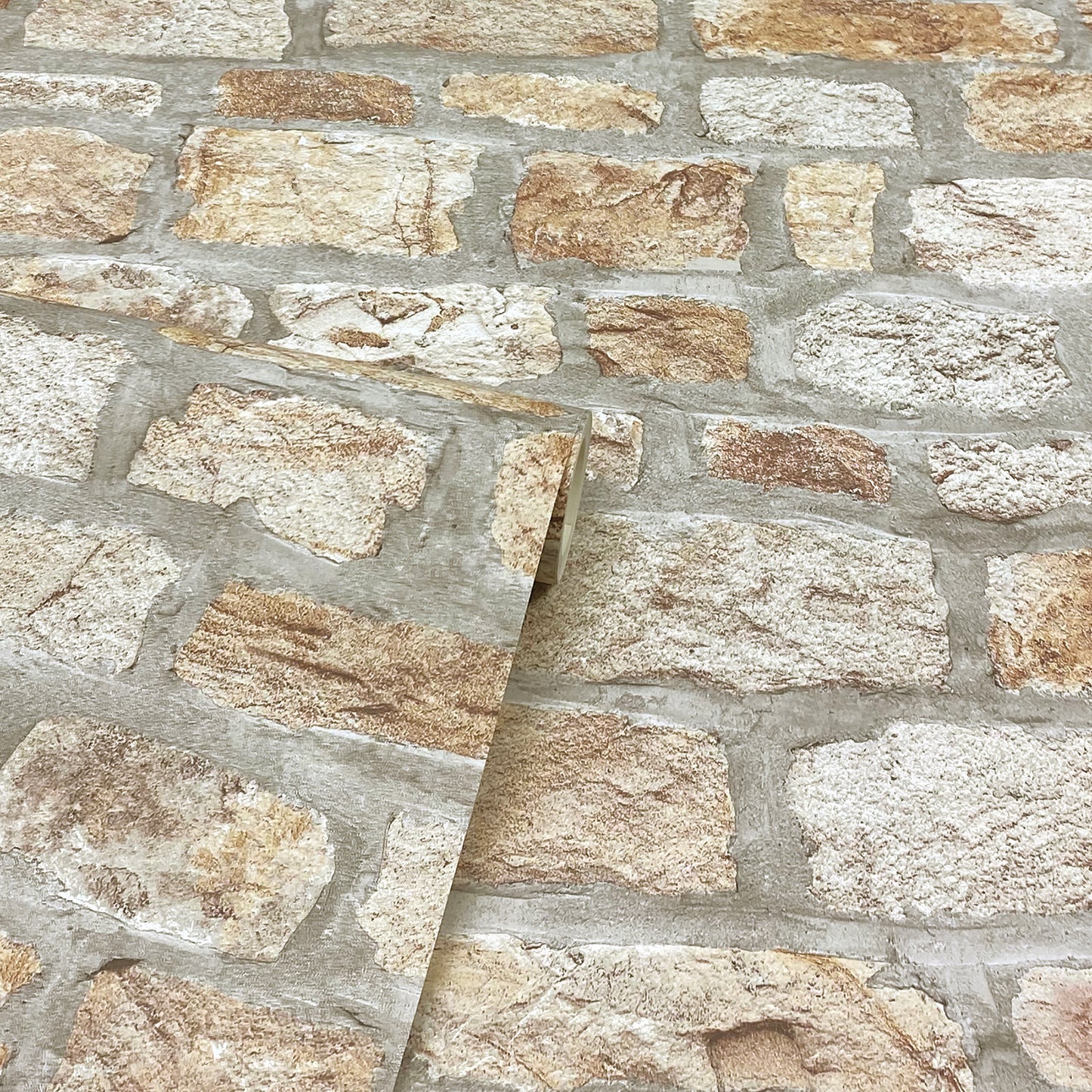 Close-up of beige & tan stone veneer wall with gray mortar; a diagonal sample panel rests on it.