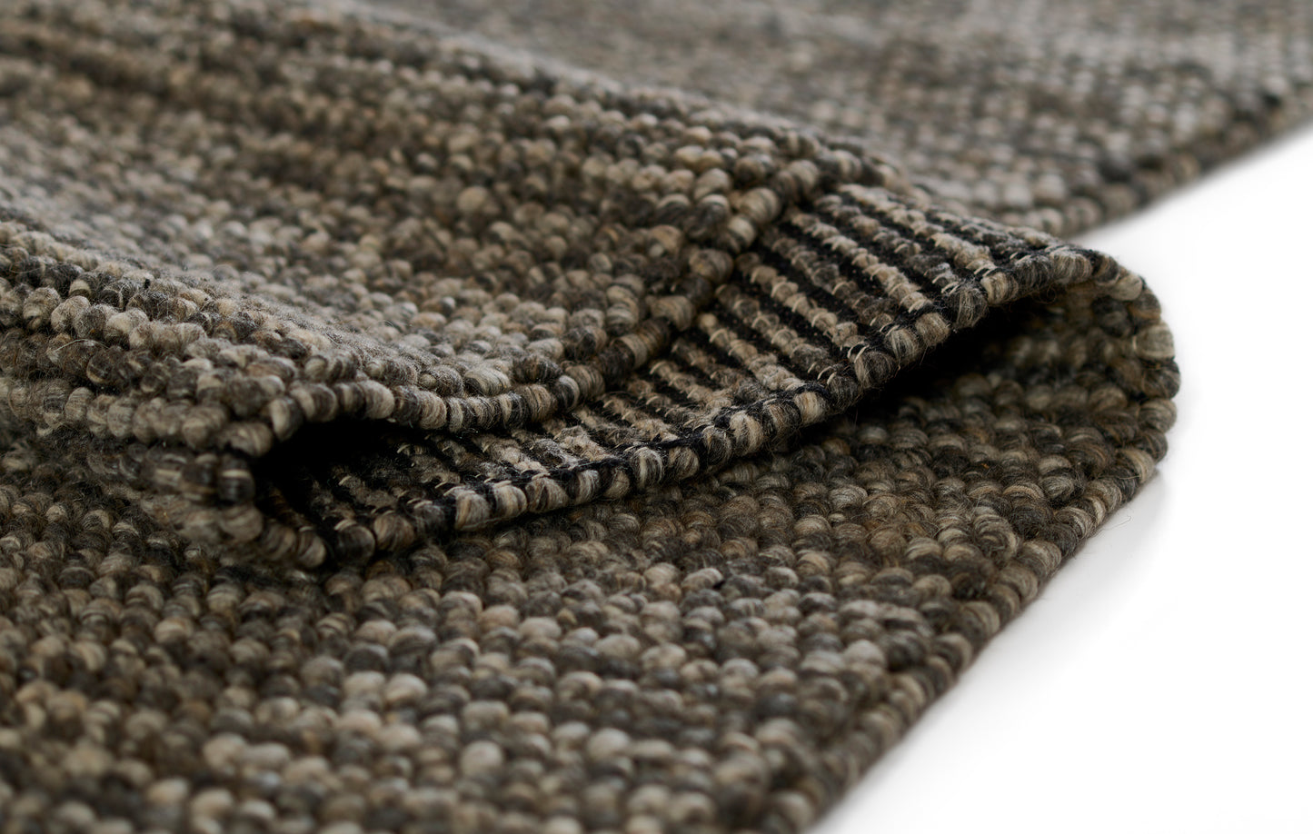 Close-up of a brown and taupe boucle woven rug with dense looped pile and rolled edge; rustic modern area rug.