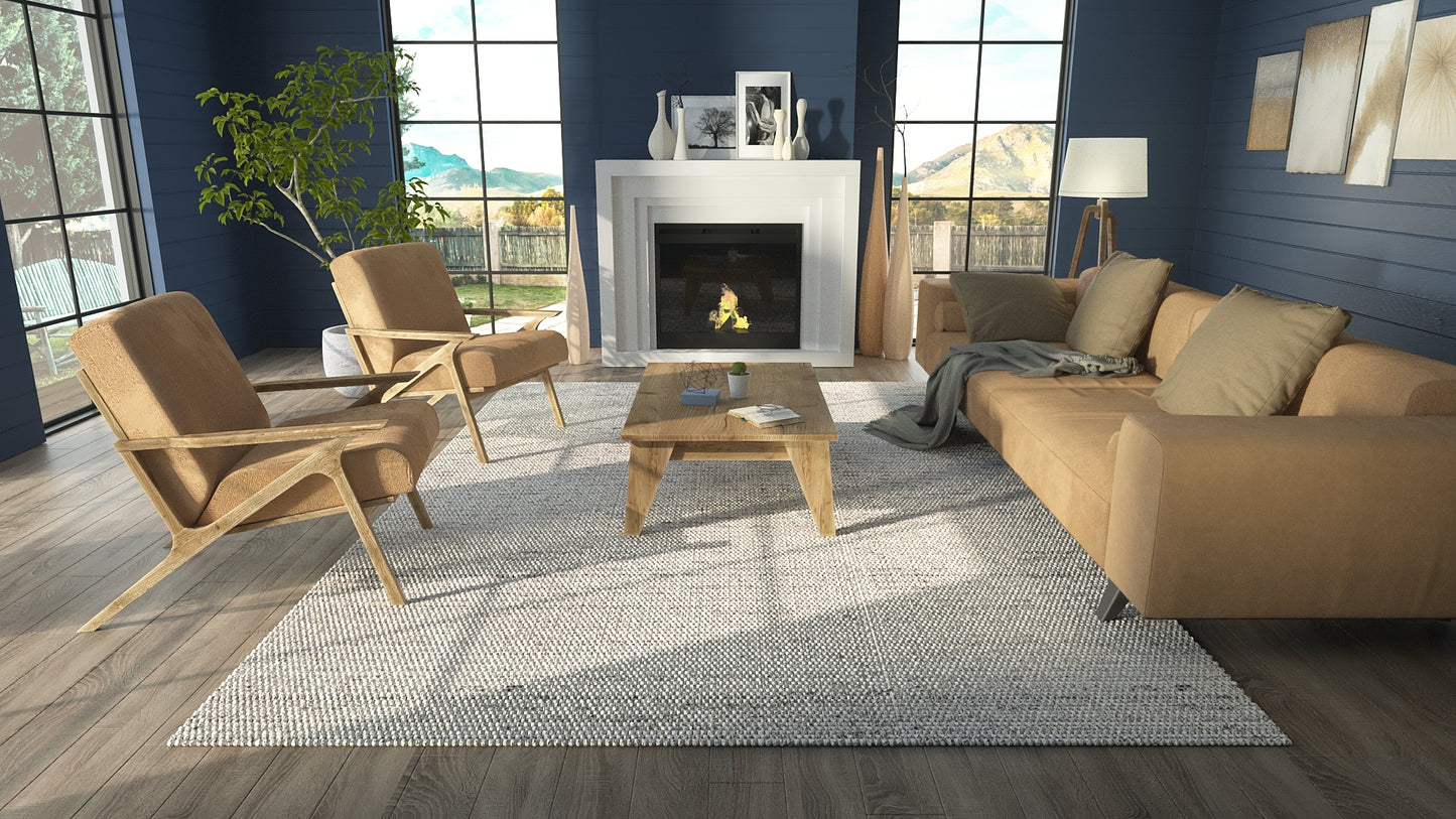 Cozy living room with navy walls, tan fabric sofa & armchairs, natural wood coffee table, gray rug, fireplace & windows.