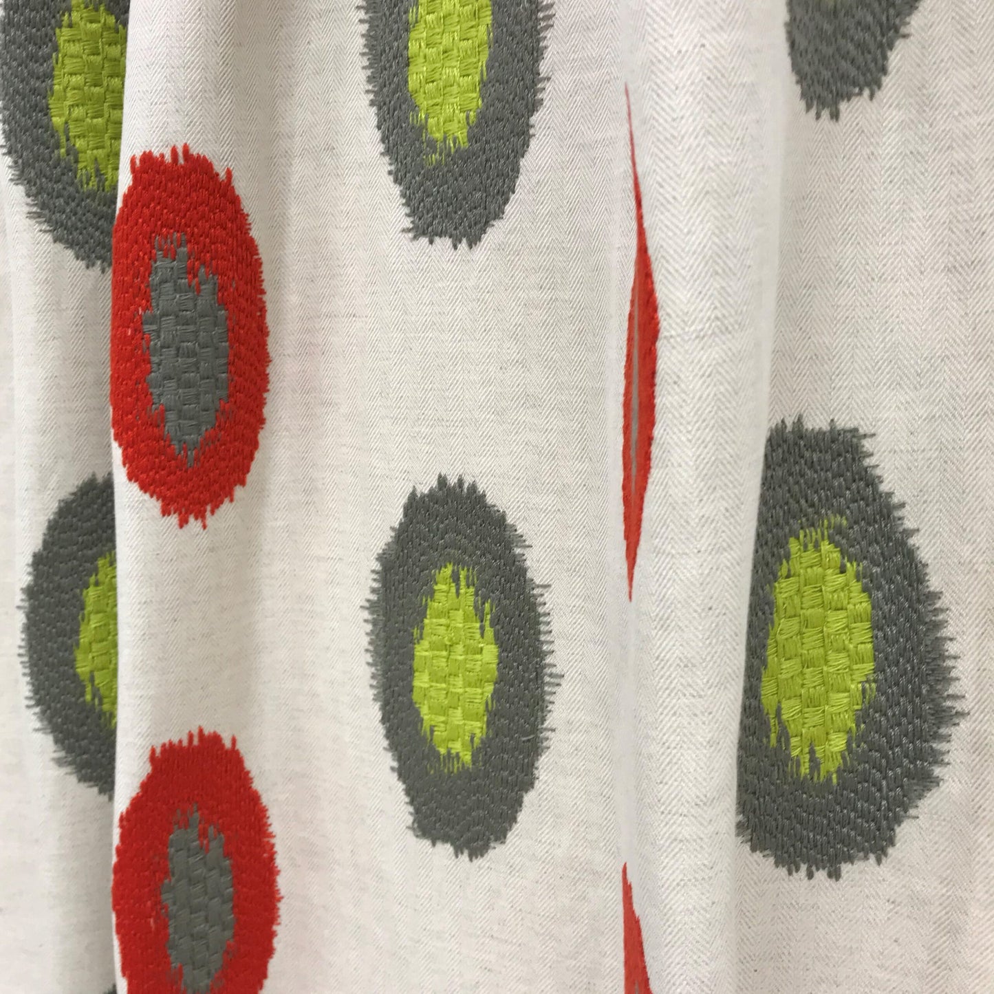 Beige textured woven fabric with red and lime-green circular dot pattern; retro geometric textile.