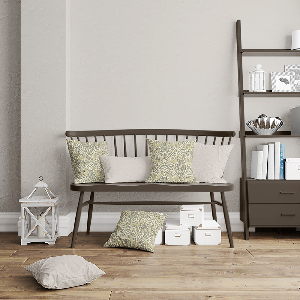 Dark brown wooden spindle-back bench with sage-green patterned and beige cushions beside a ladder bookshelf and boxes.