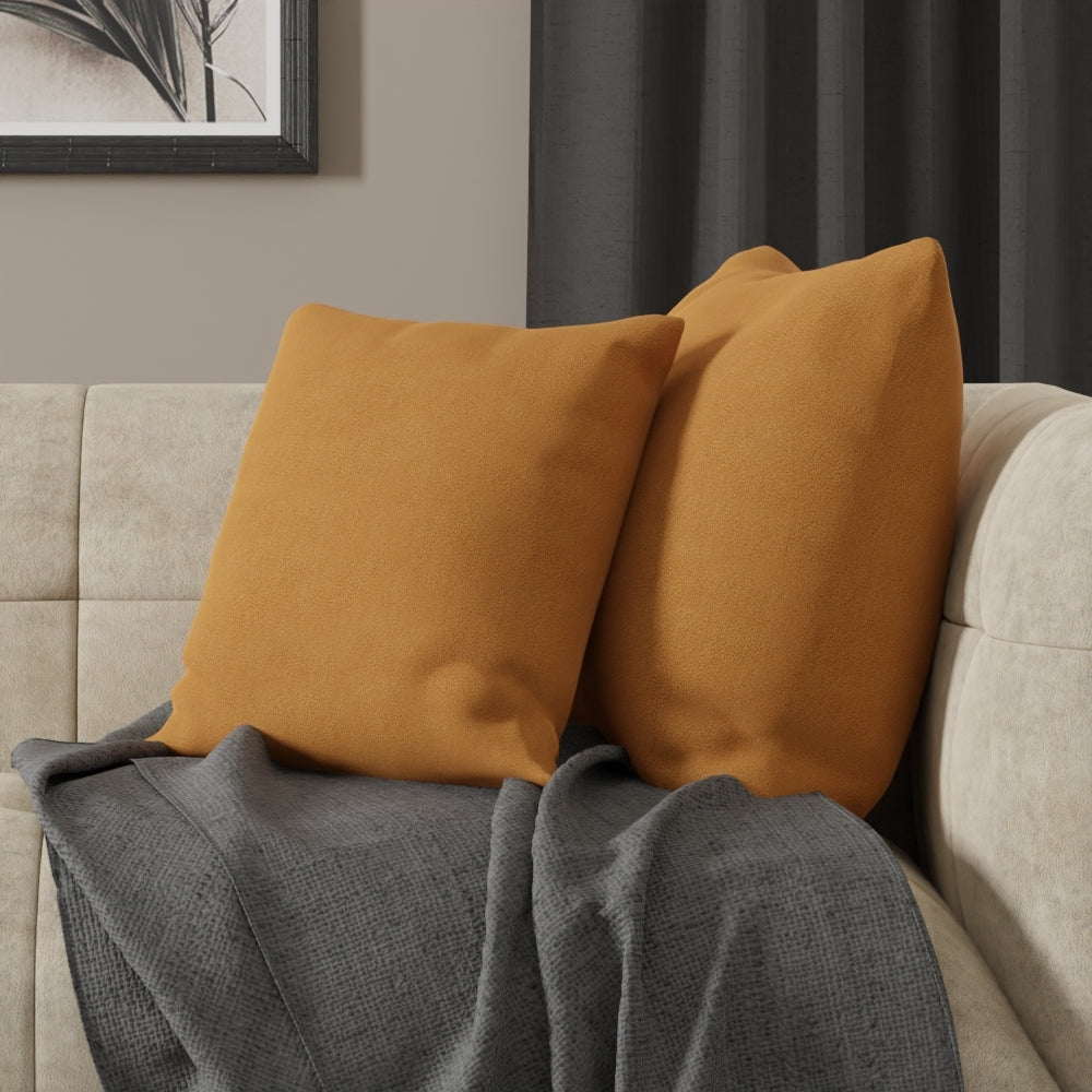 Mustard curry solid fabric on square throw pillows on a beige sofa with a gray knit blanket in a cozy modern living room.