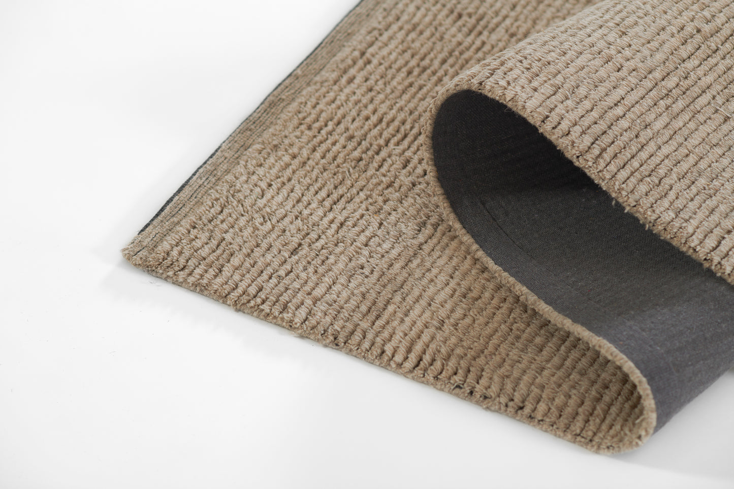 Beige ribbed corduroy rug partially rolled, showing textured pile and dark grey underside.