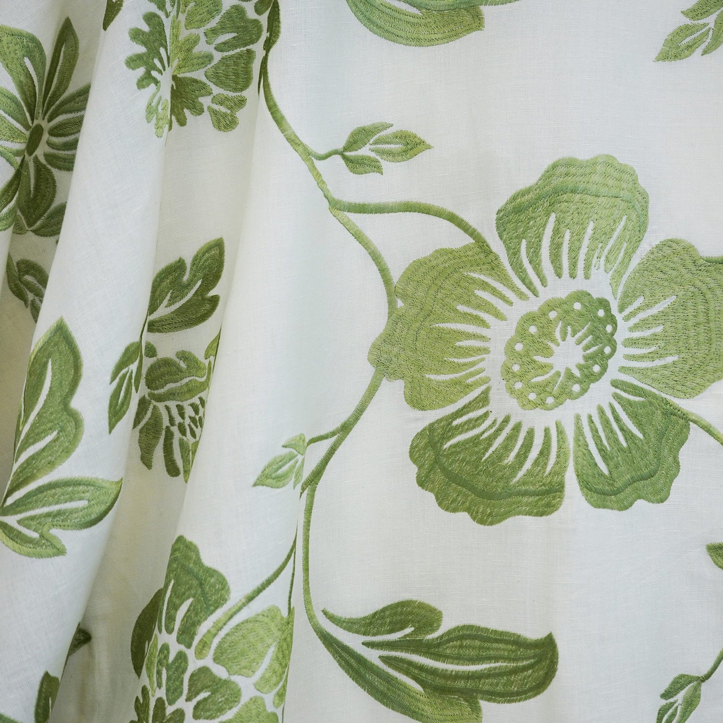 Cream/beige linen fabric with a large green botanical floral print featuring vines, leaves and a bold bloom.