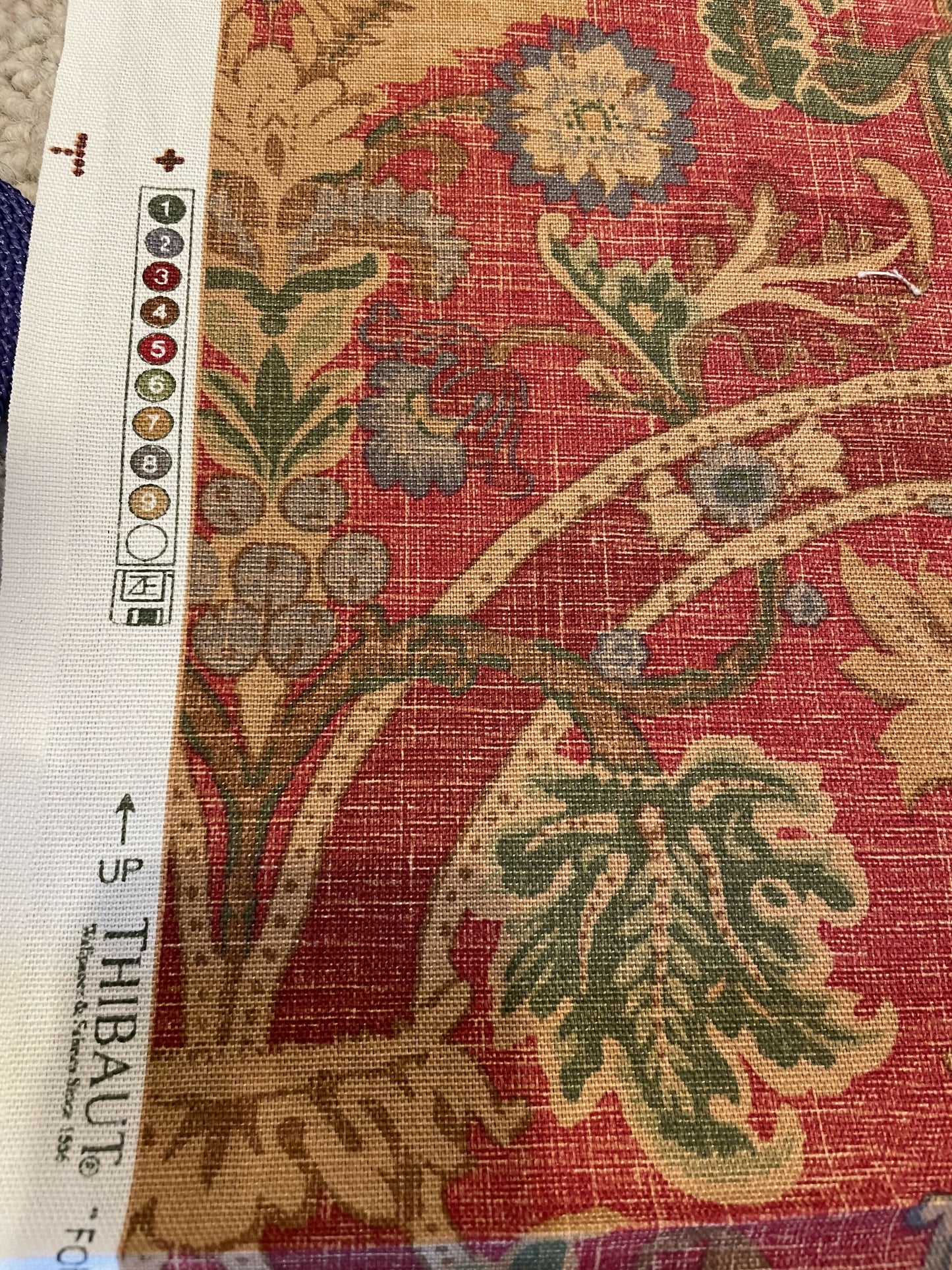 Red and tan printed floral fabric with a woven texture and marked alignment guide.