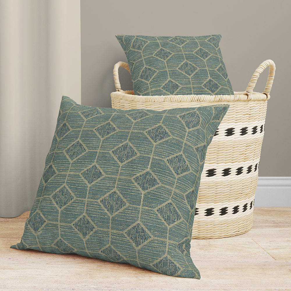 Blue geometric fabric with a repeating pattern on a light wood floor, placed near a woven straw basket.