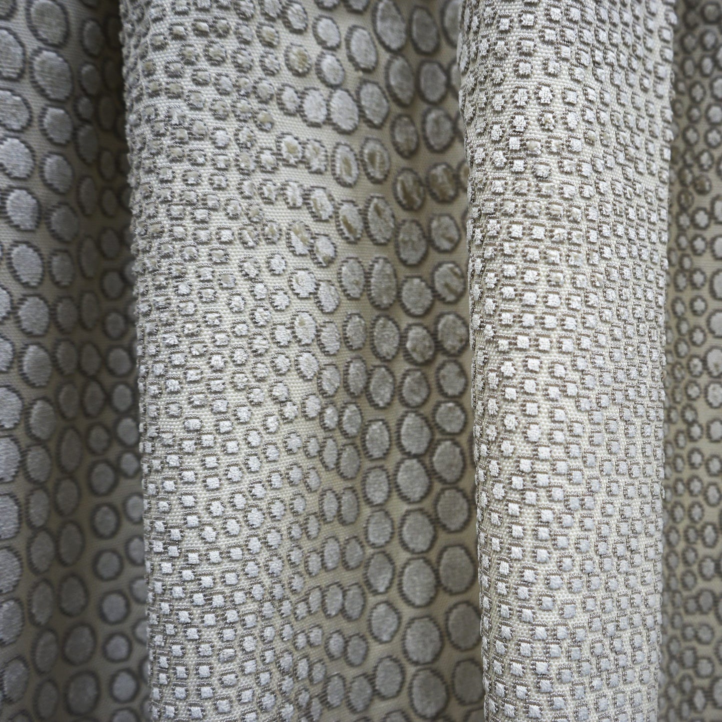Beige cheetah-print curtain fabric with gray spots, textured velvet-like drapery material.