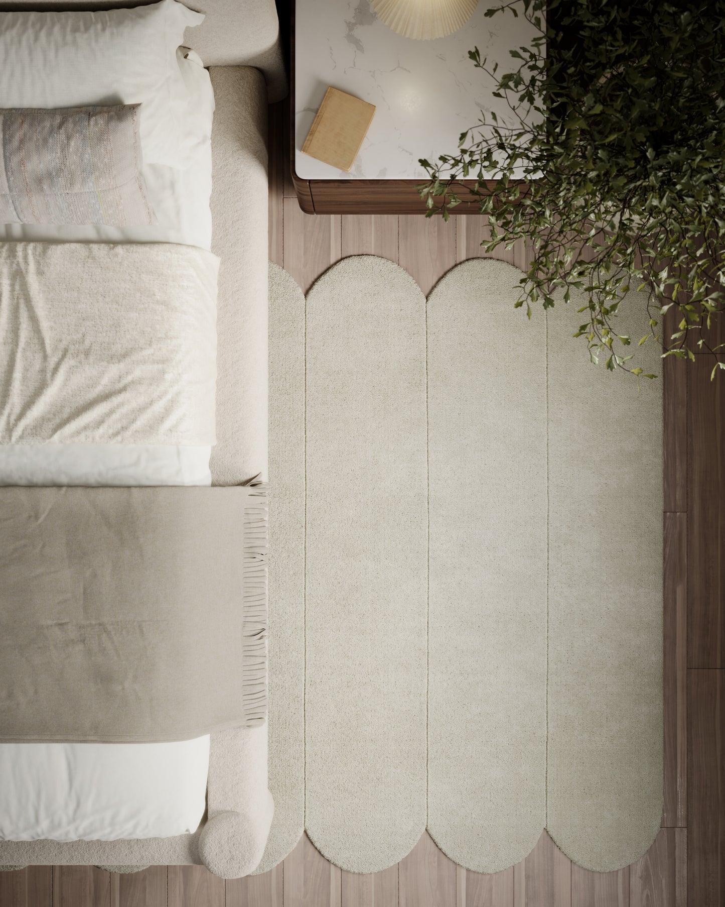 Overhead view of beige scalloped rug beside a white bed; wooden nightstand with lamp, book & lush plant.