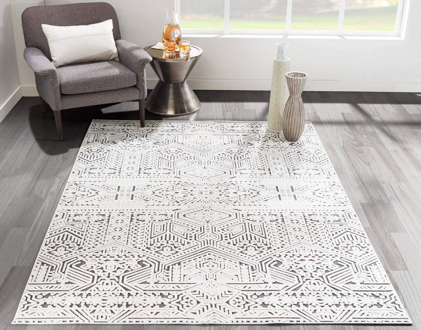 Geometric gray-and-white rug as the main focus, with a gray upholstered armchair beside a metal side table.
