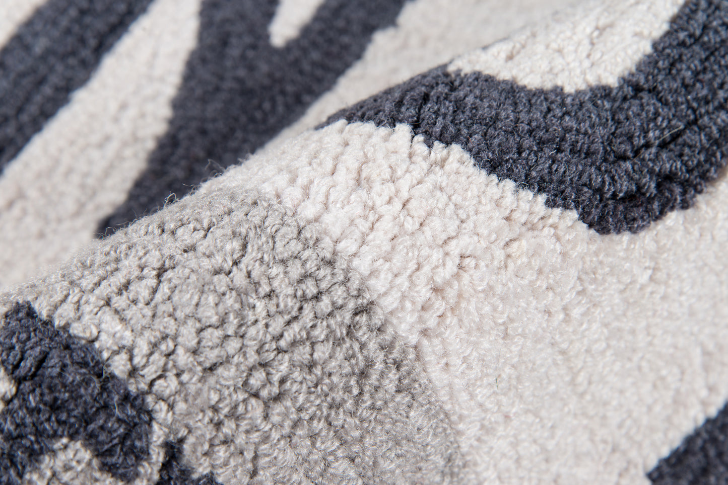 Close-up of a plush boucle rug with an abstract navy, gray, and ivory pattern in thick loop pile.