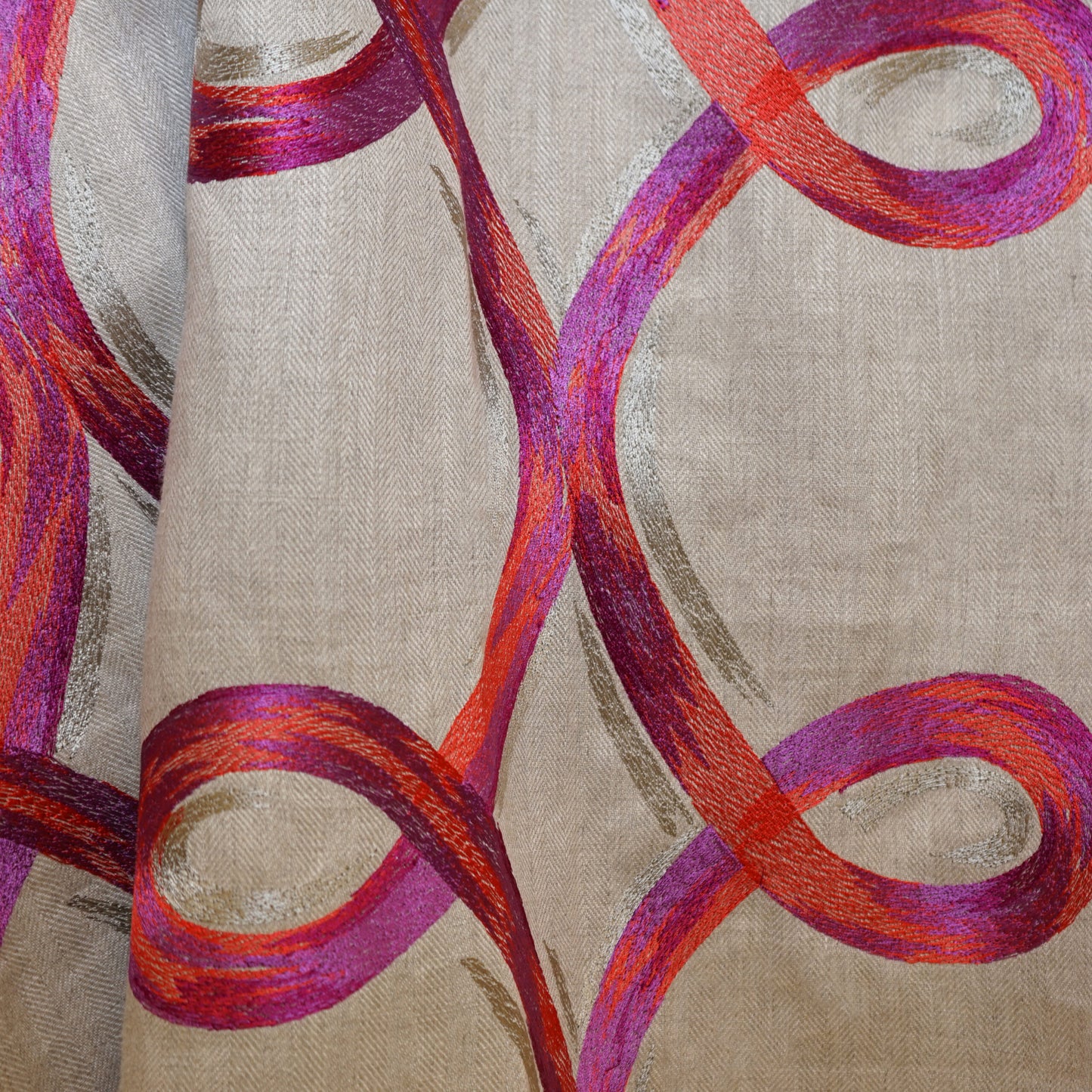 Beige drapery fabric with bold magenta and orange curved looping ribbon patterns.
