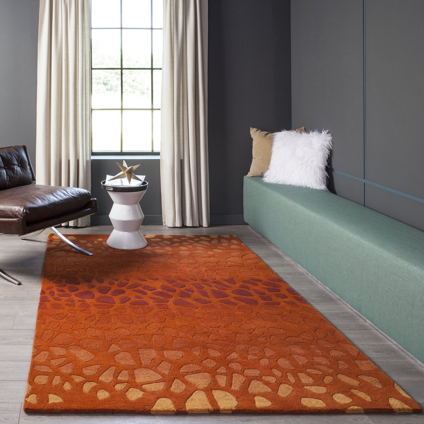 Modern living room with orange patterned rug, green bench, brown leather chair, beige curtains and white star decor.