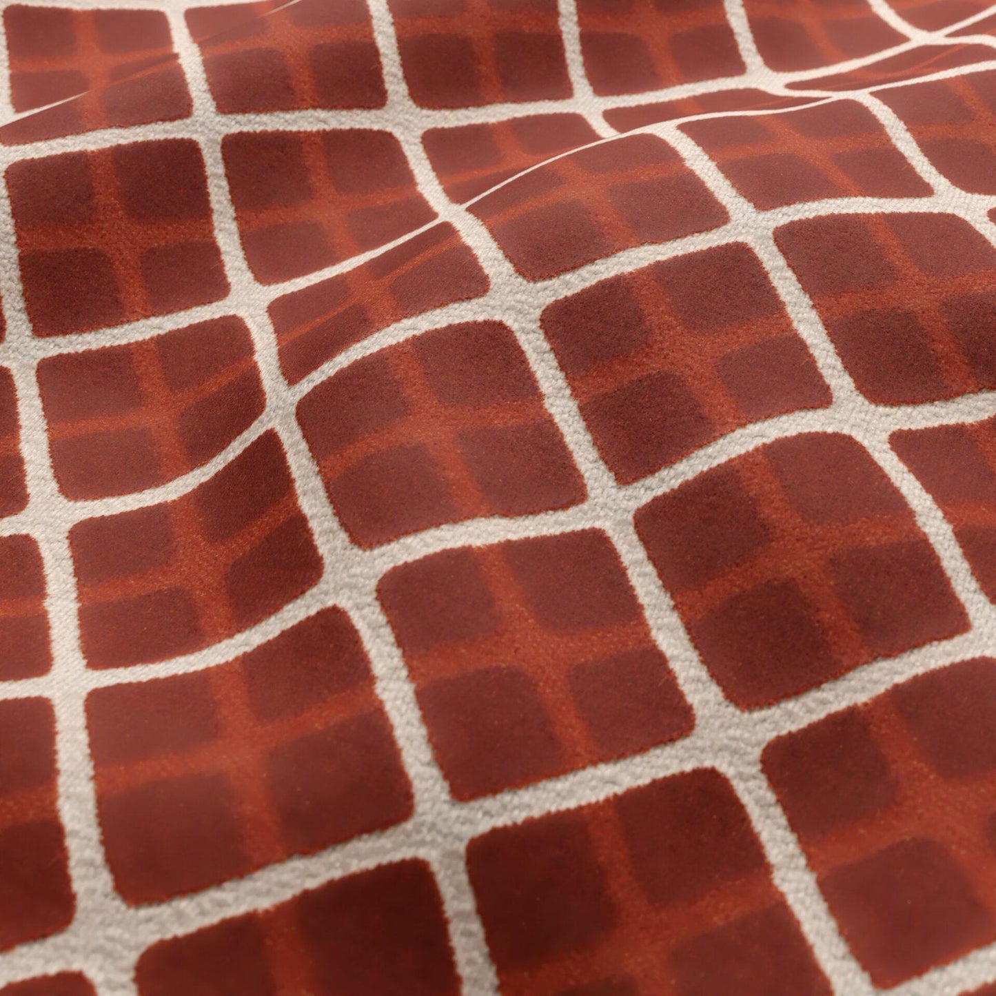 Close-up of orange and cream velvet fabric texture with a geometric diamond pattern.