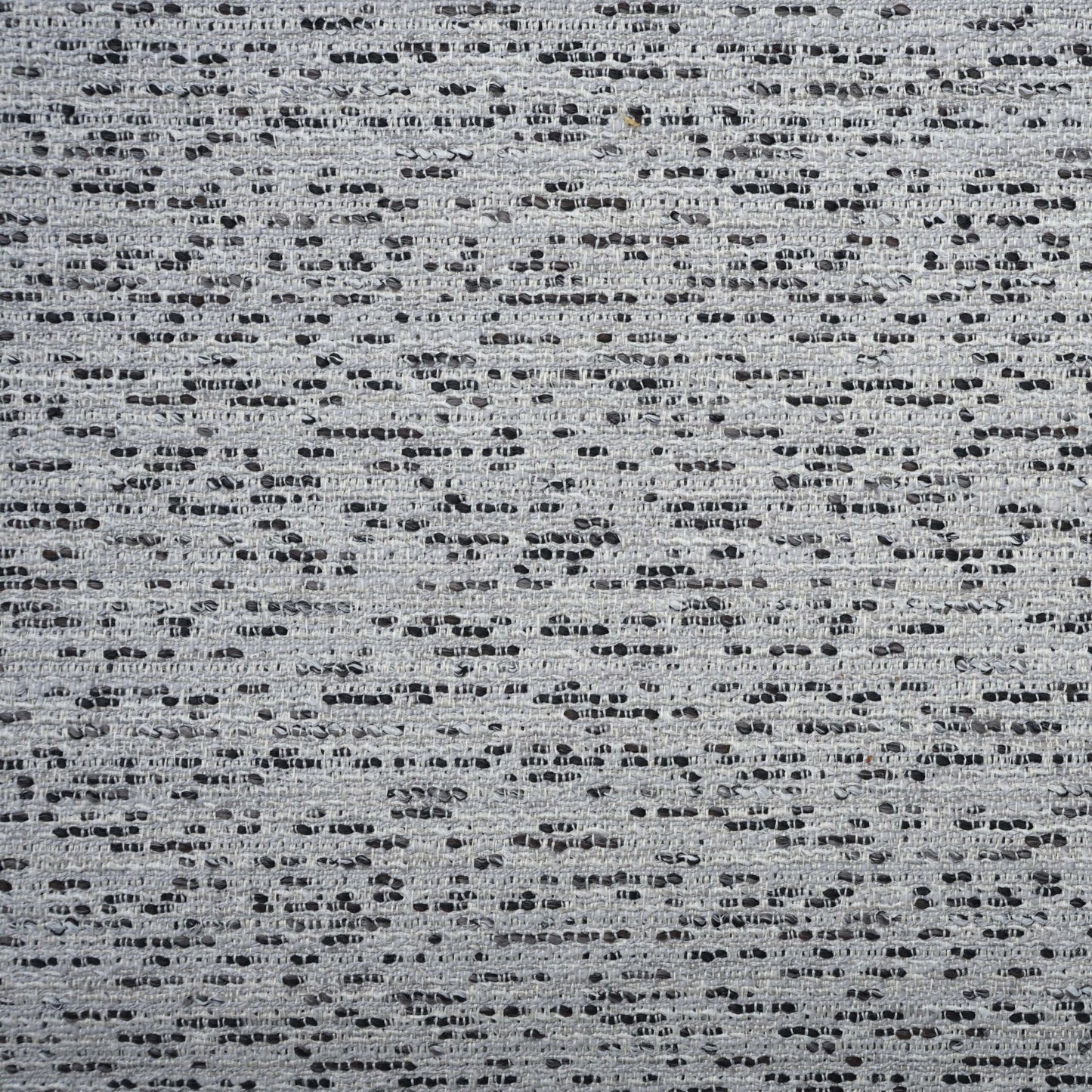 Grey dotted boucle fabric with tiny black specks and a textured woven surface.