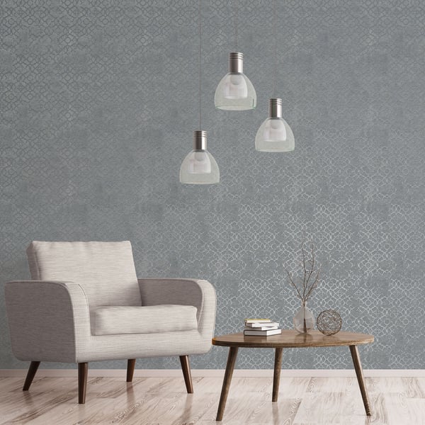 Beige mid-century armchair with wooden legs beside a round coffee table; gray geometric wallpaper and glass pendant lights.