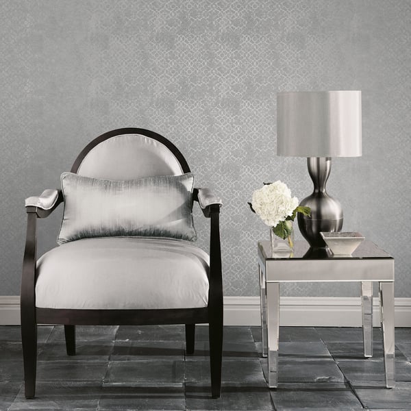 Modern glam living room: black-framed armchair with white cushions beside a chrome side table, lamp, and white flowers.