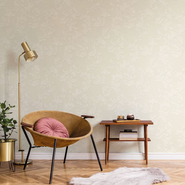 Mustard circular chair with pink tufted cushion, black legs, beside side table, gold floor lamp, plant, damask wallpaper.
