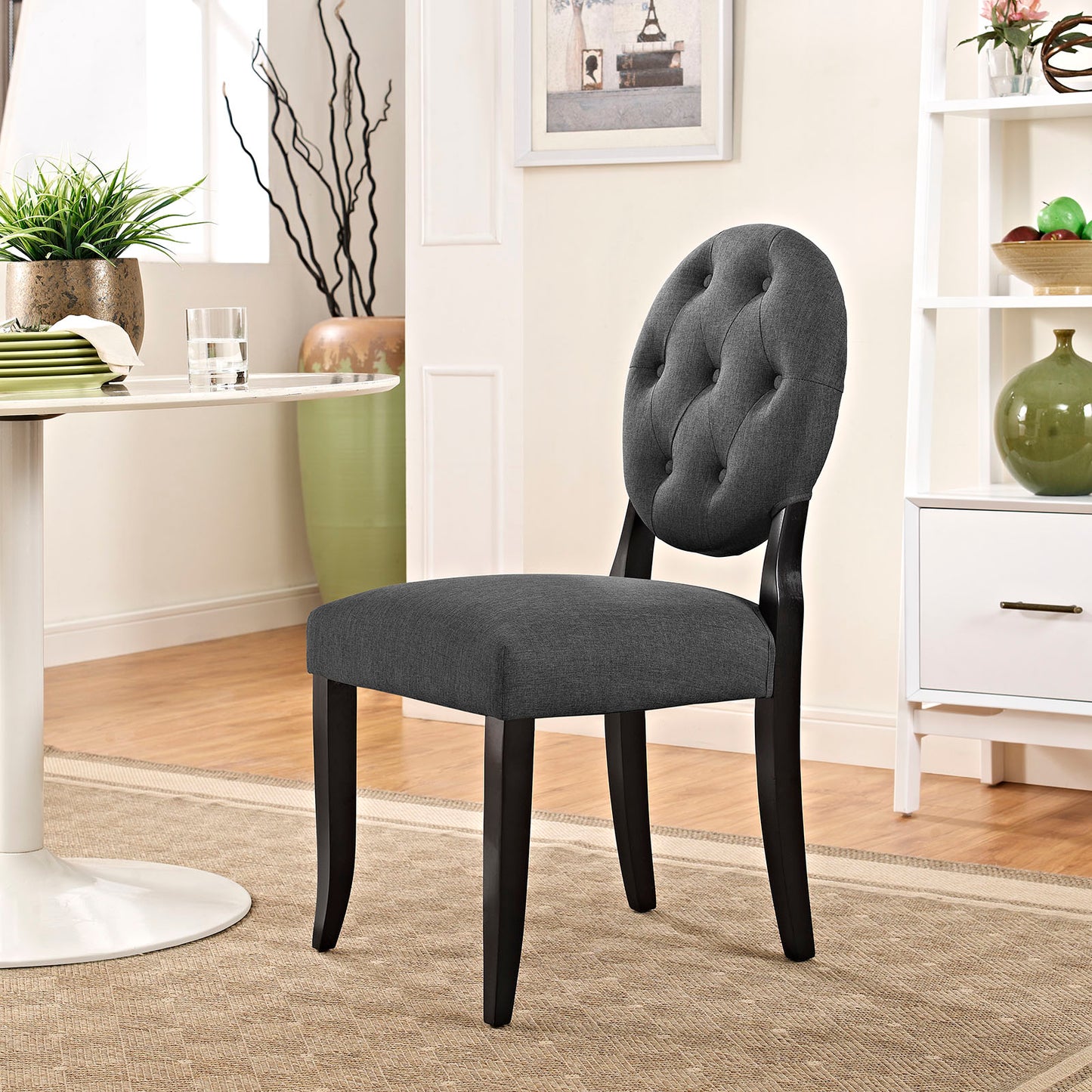 Gray fabric tufted back dining chair with black curved legs in a modern home dining area.