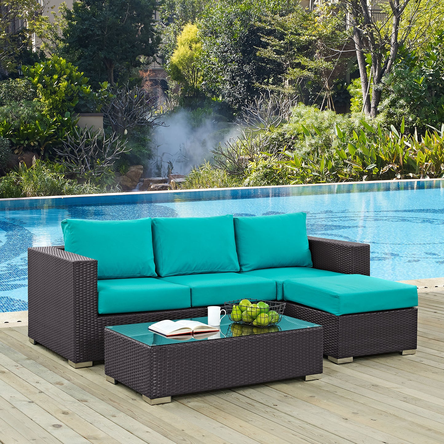 Dark brown woven rattan outdoor sectional with turquoise cushions and glass-topped coffee table beside a pool.