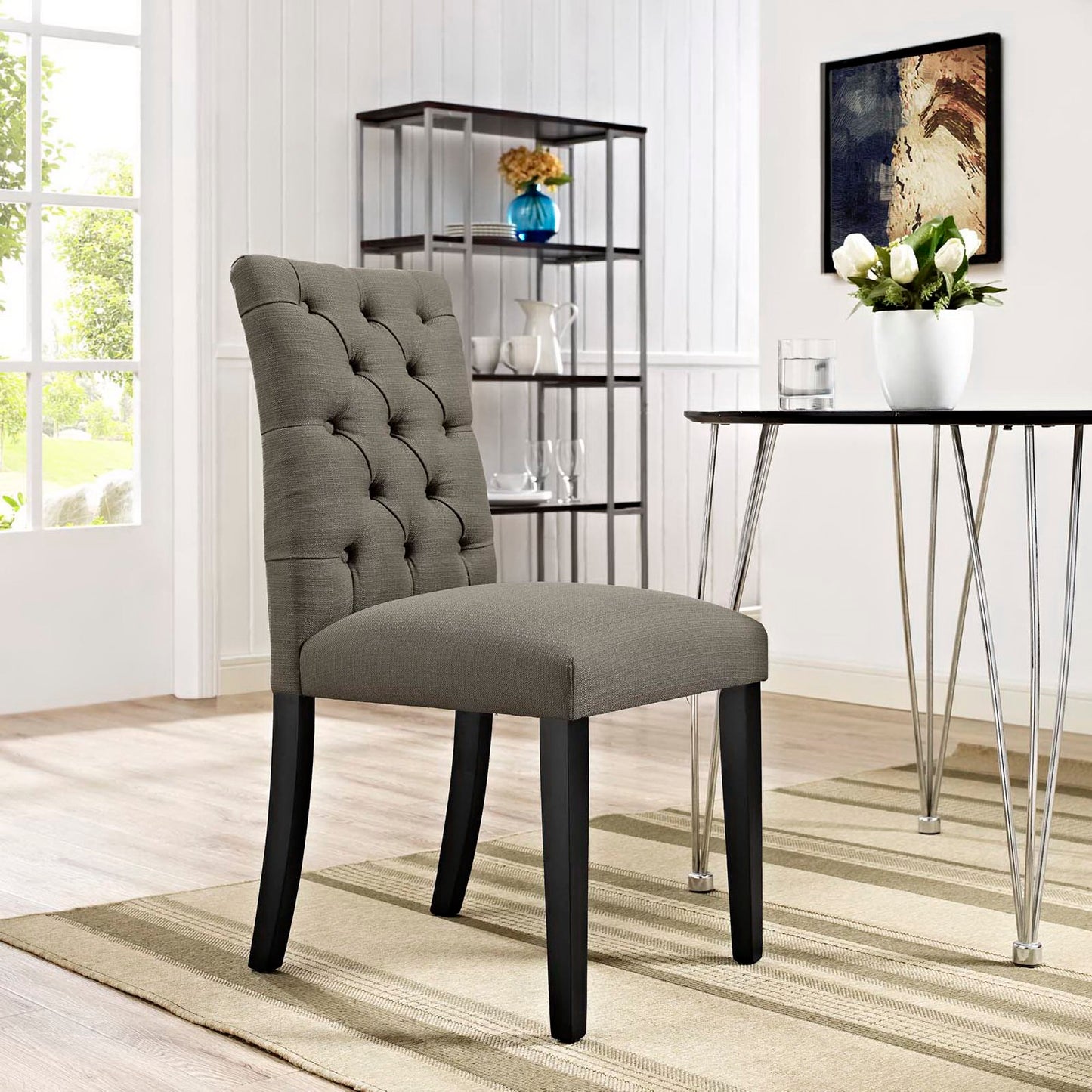 Fabric upholstered tufted dining chair with black legs in a modern dining room.