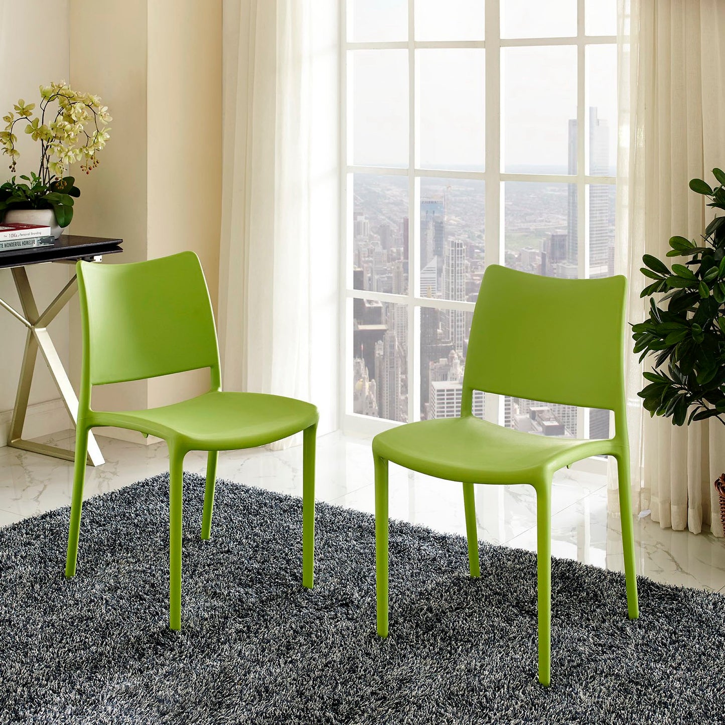 Two lime green molded plastic chairs with slender legs in a bright modern room by large windows, gray rug and plants.