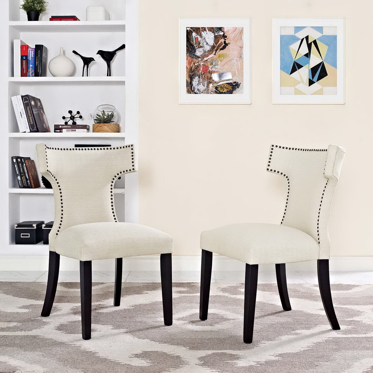 Pair of brown upholstered dining chairs with dark wood legs, curved backs and nailhead trim, shown in a stylish living room.