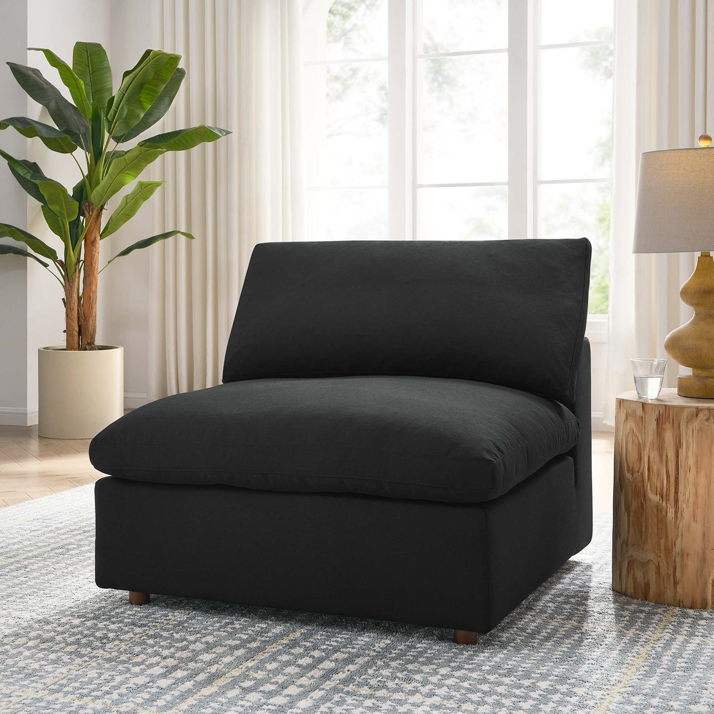 Black upholstered armless modern lounge chair with thick back cushion on short wooden legs.