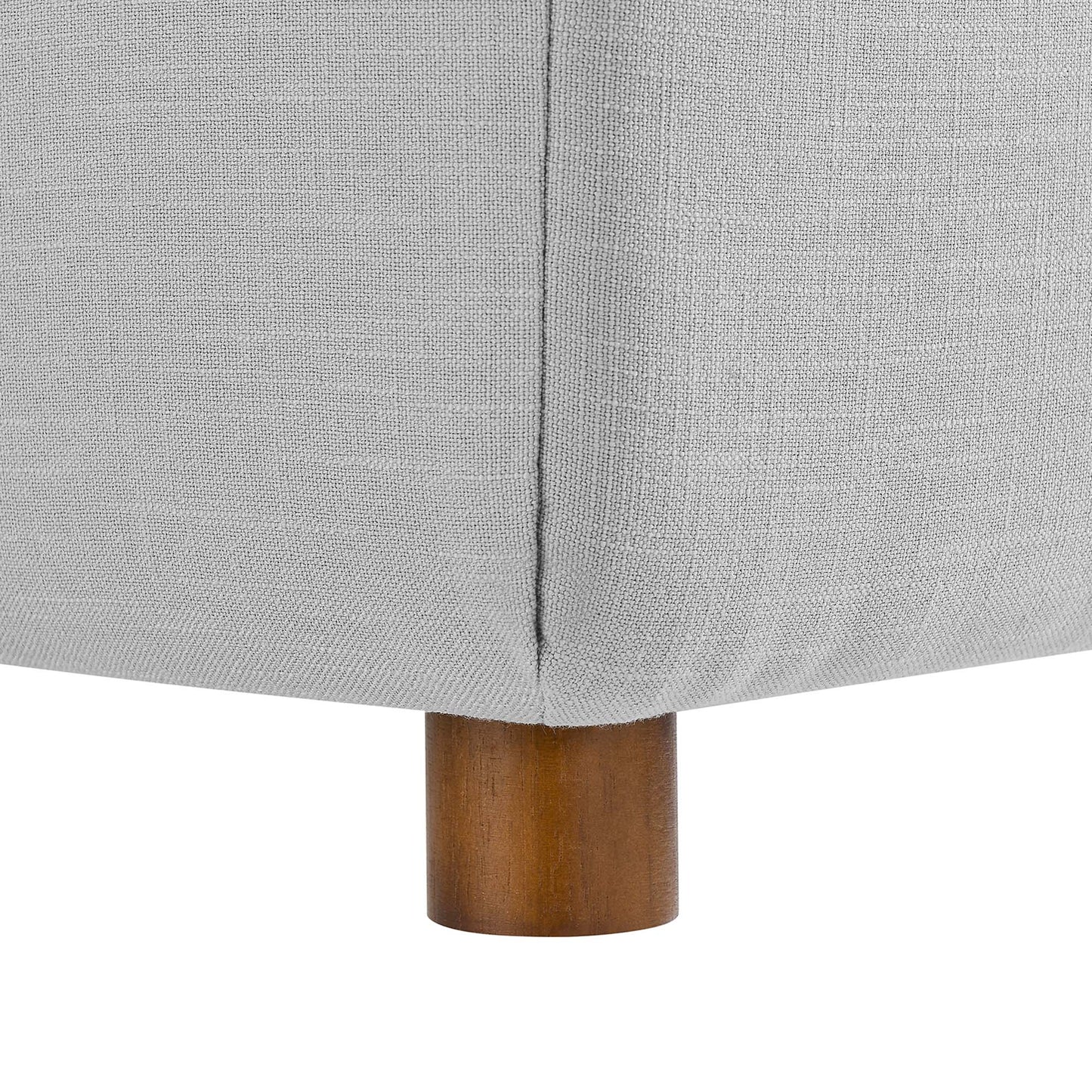 Light gray fabric upholstered sofa corner with visible seam and a short round wooden leg