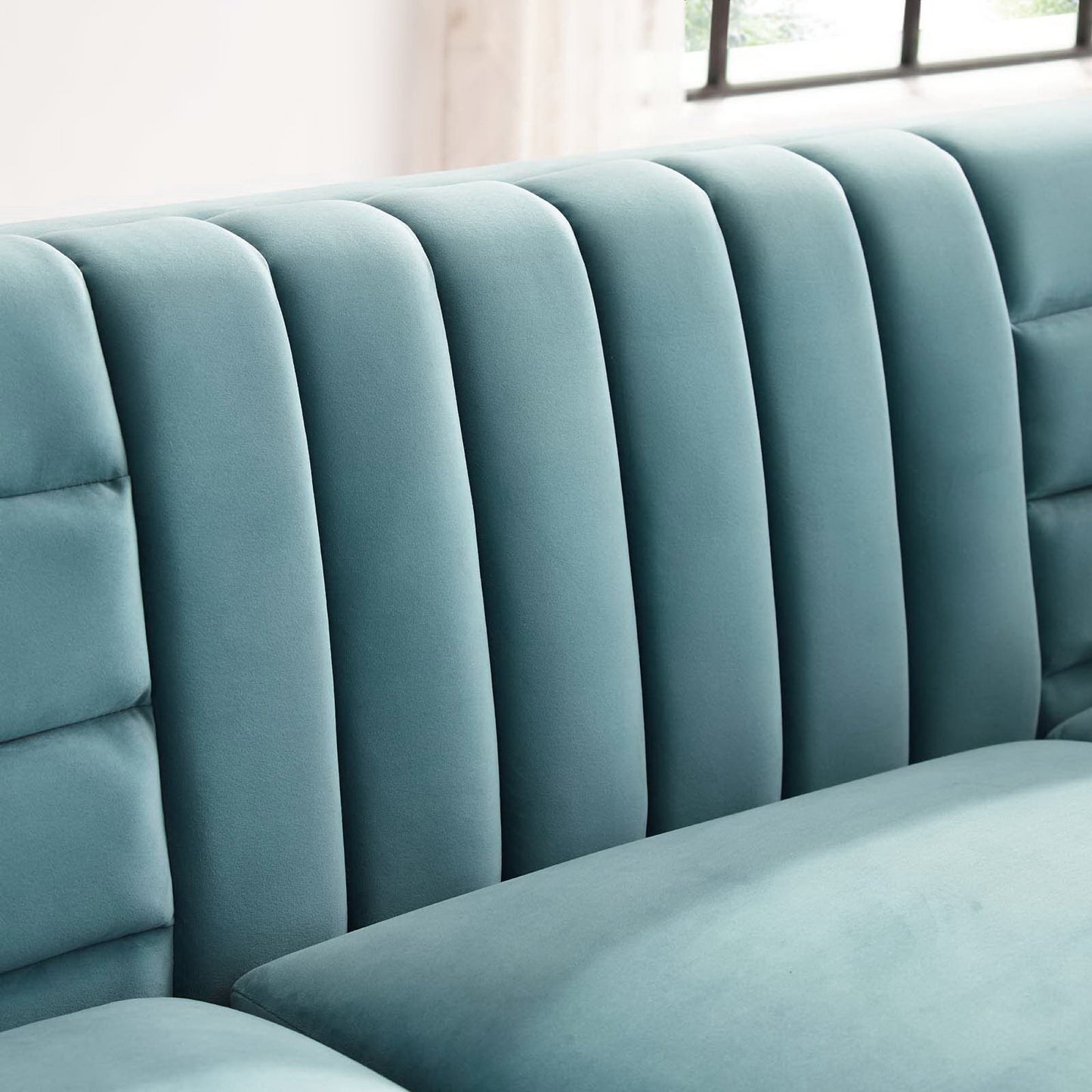 Blue velvet sofa with tall vertical channel-tufted back cushions, modern lounge seating.