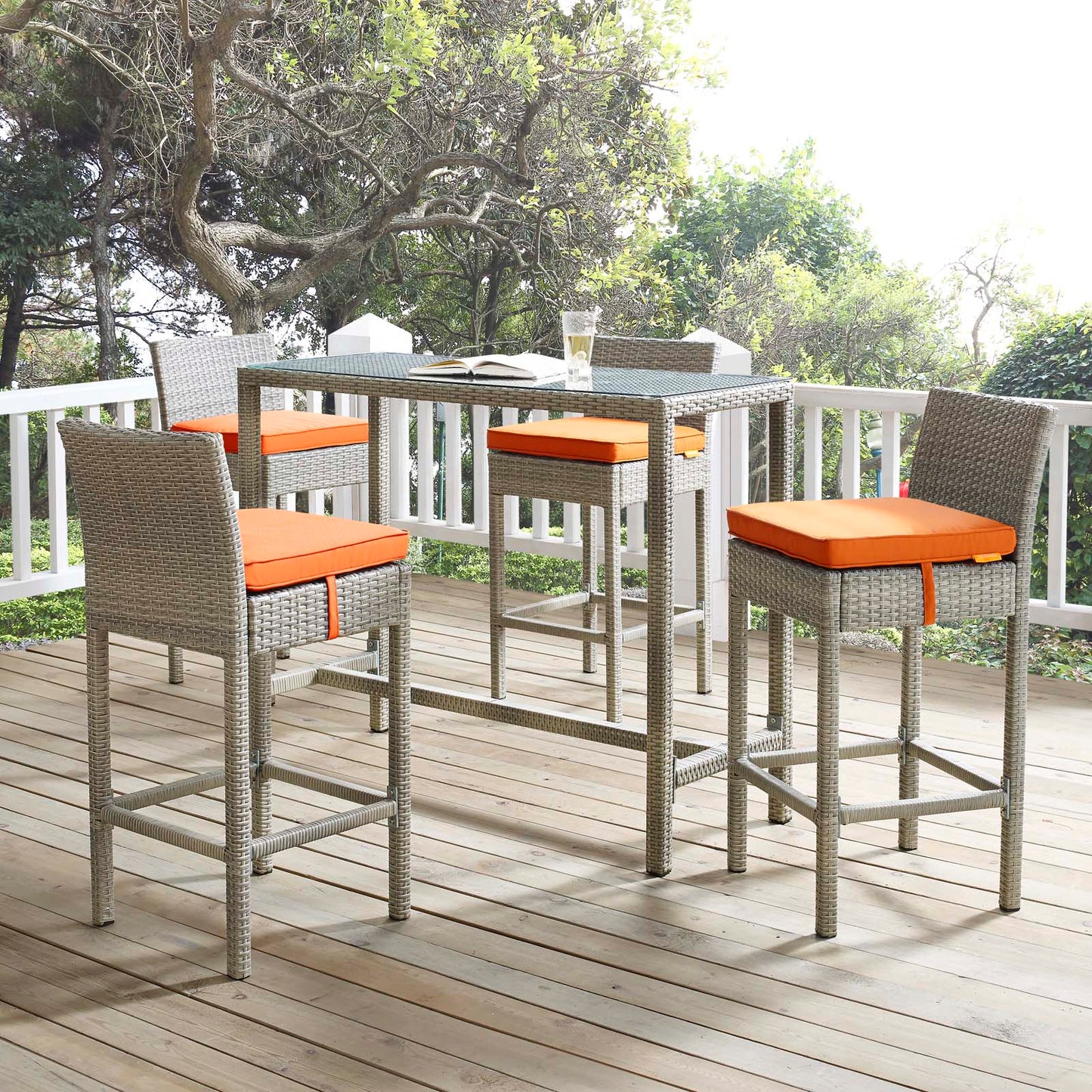 Outdoor gray-wicker bar-height stools set of 4 with orange cushions on a wooden deck.