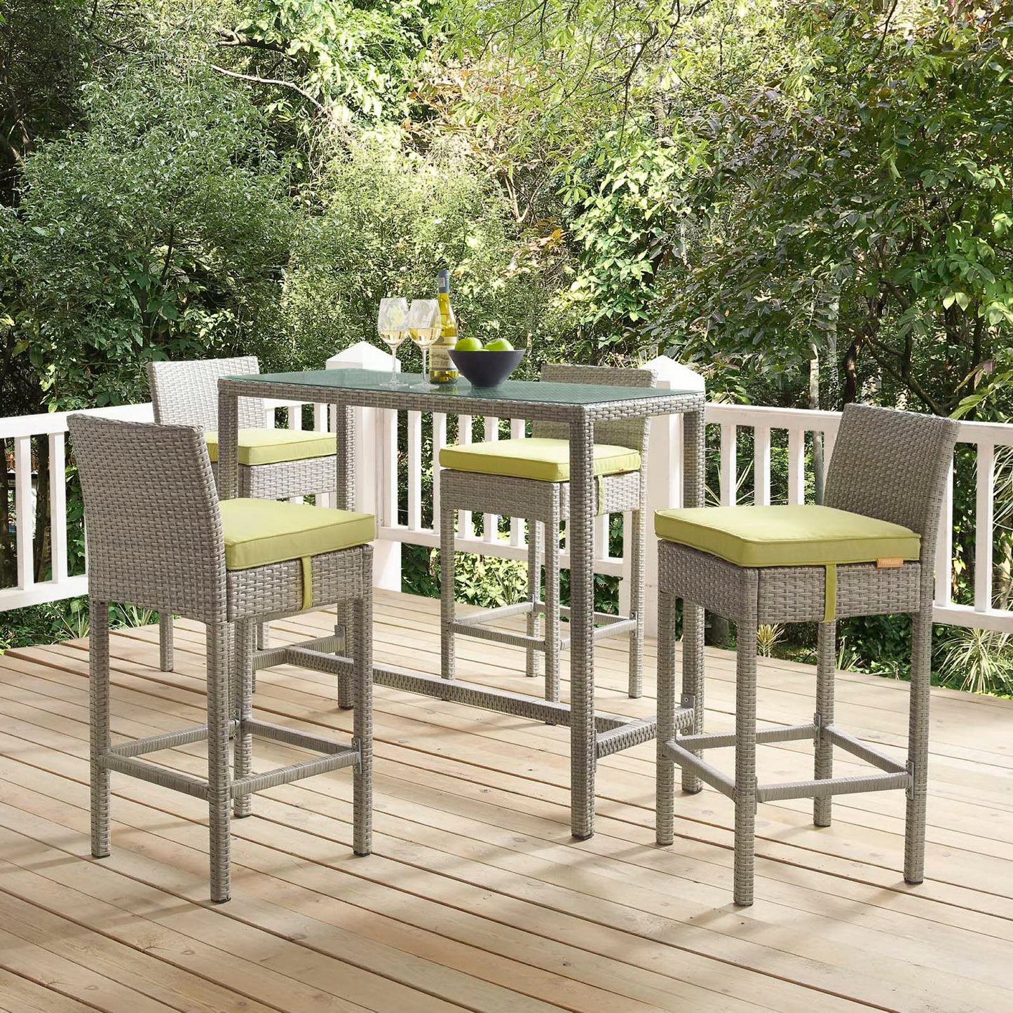 Outdoor grey wicker bar stools set of four on a wooden deck amid lush greenery