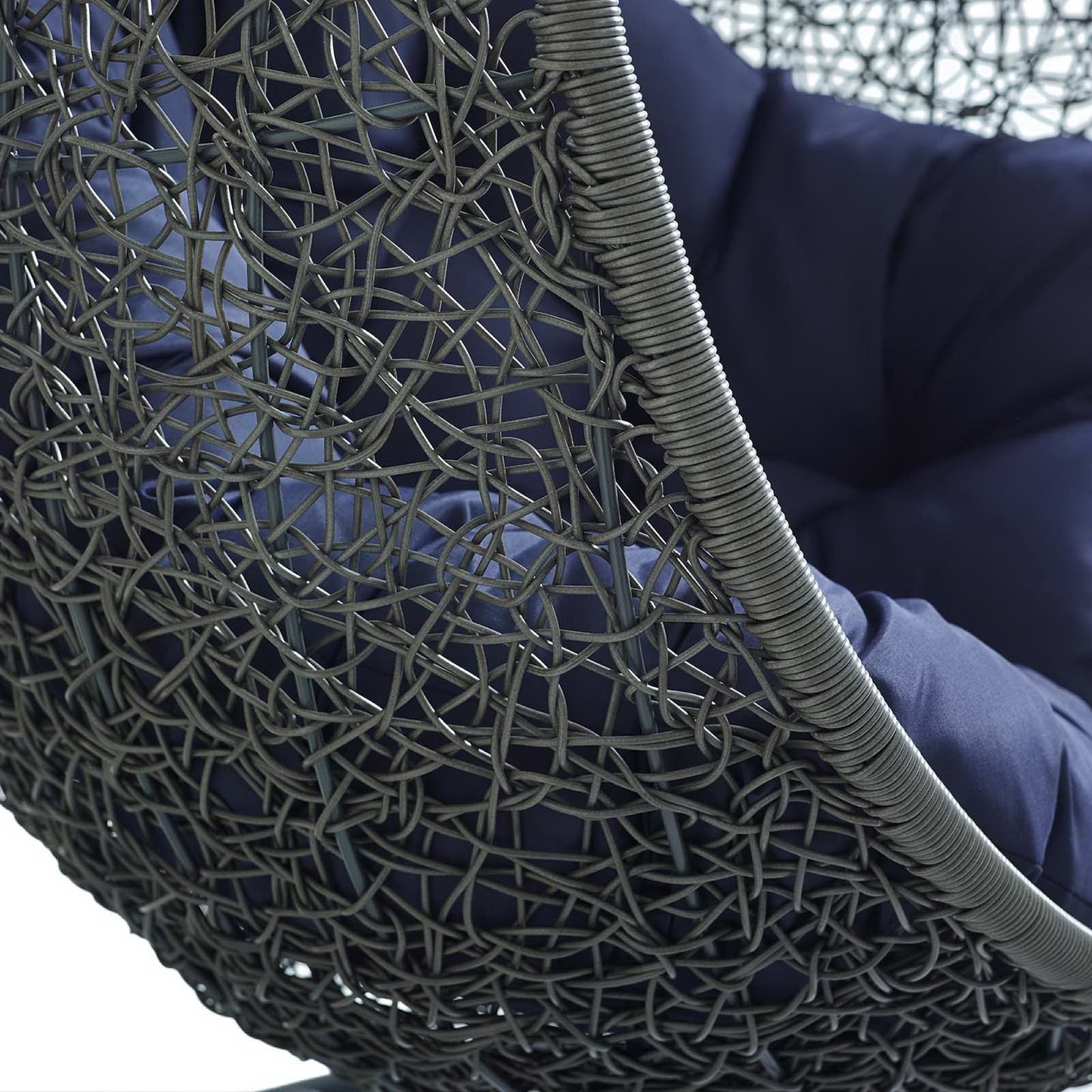 Close-up of gray woven rattan-style outdoor lounge chair with navy cushion