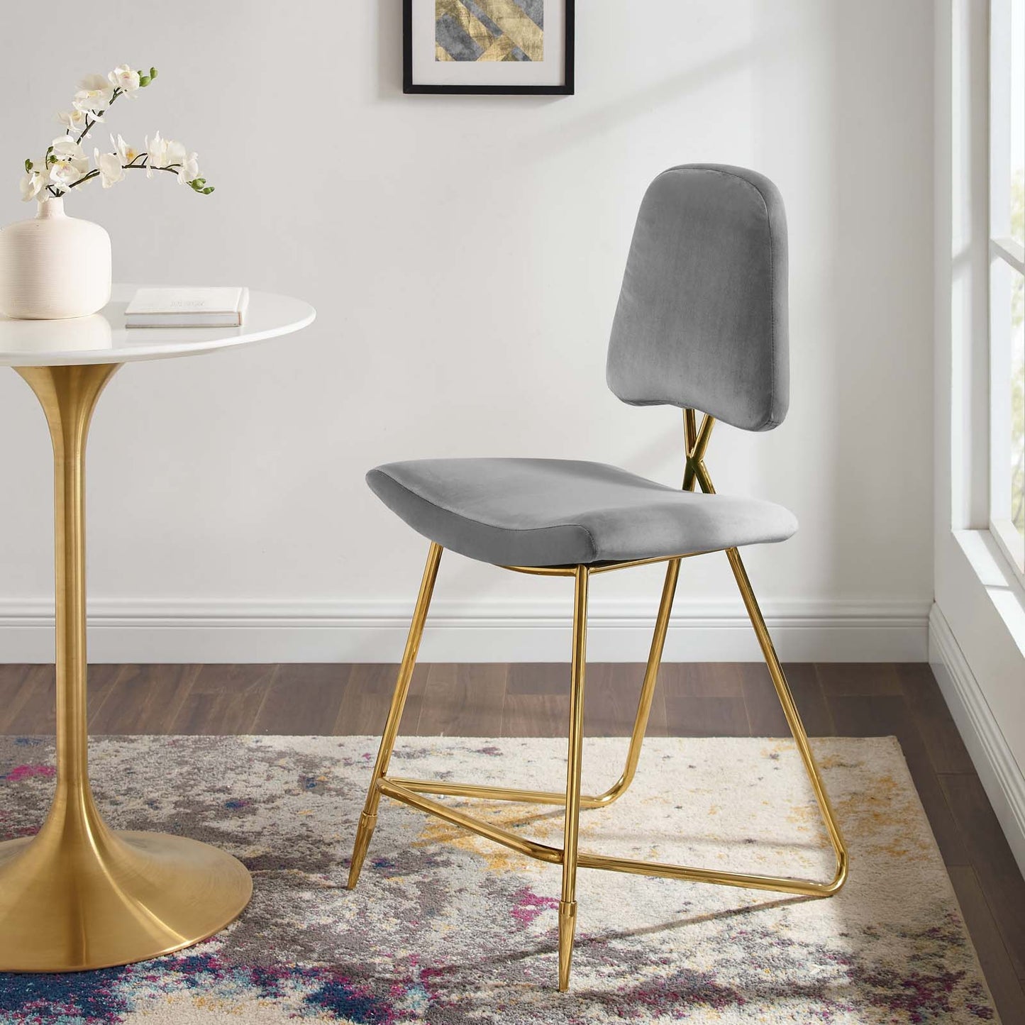Gray upholstered counter stool with slim gold metal legs in a modern mid-century style.