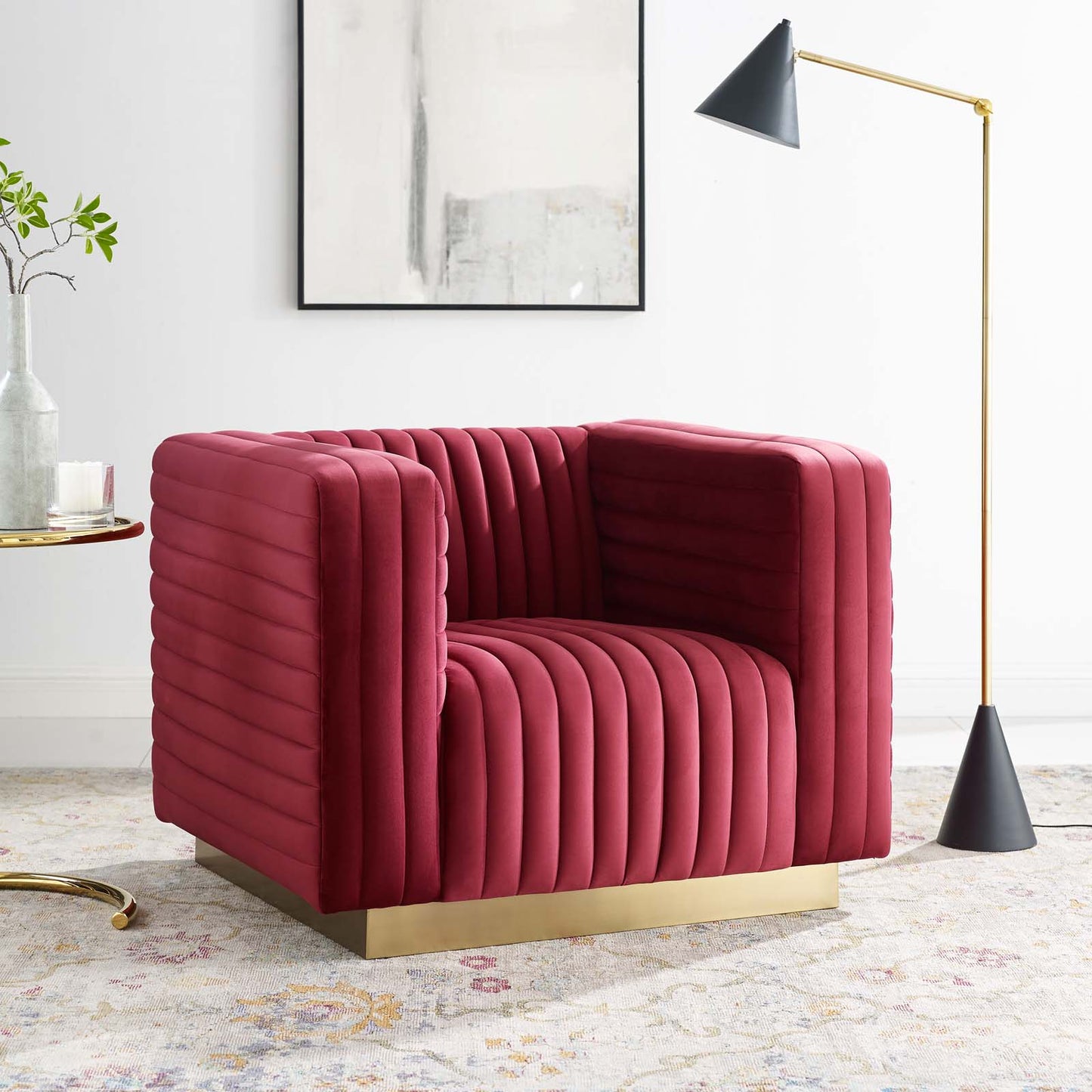 Deep red velvet channel-tufted armchair with a gold metal base, modern glam living-room setting.