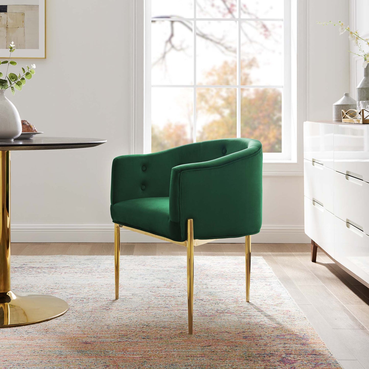 Emerald green velvet armchair with tufted back and gold metal legs in a modern living room.