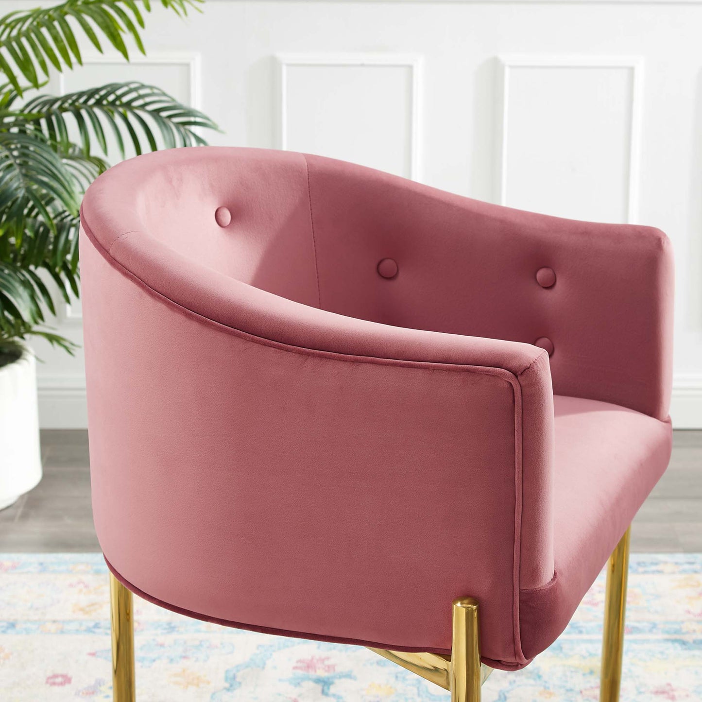 Dusty rose velvet tufted counter stool with curved back and gold legs, indoor dining setting.