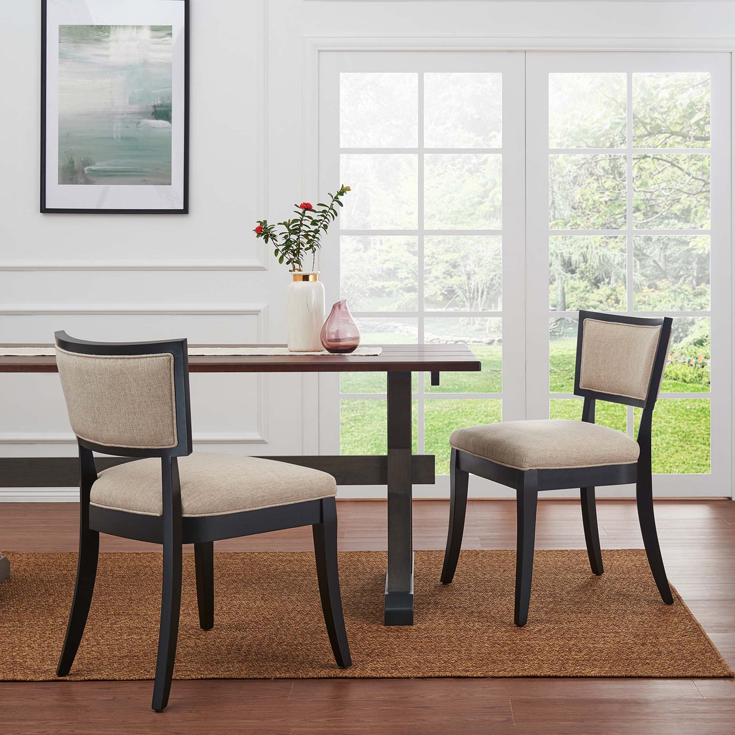 Pair of dark wood dining chairs with beige upholstered fabric seats, on a brown jute rug.