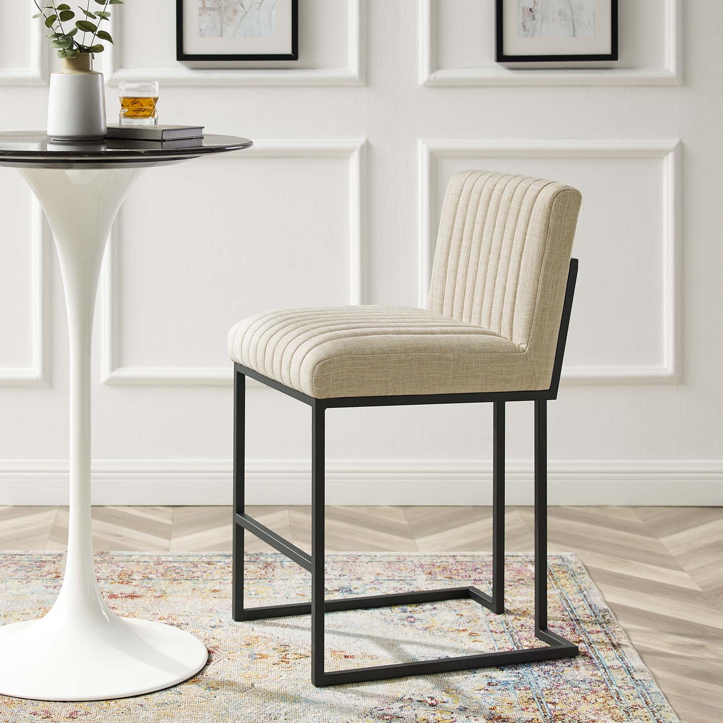 Beige fabric counter stool with black metal cantilever frame & vertical channel tufting; shown with a white pedestal table.