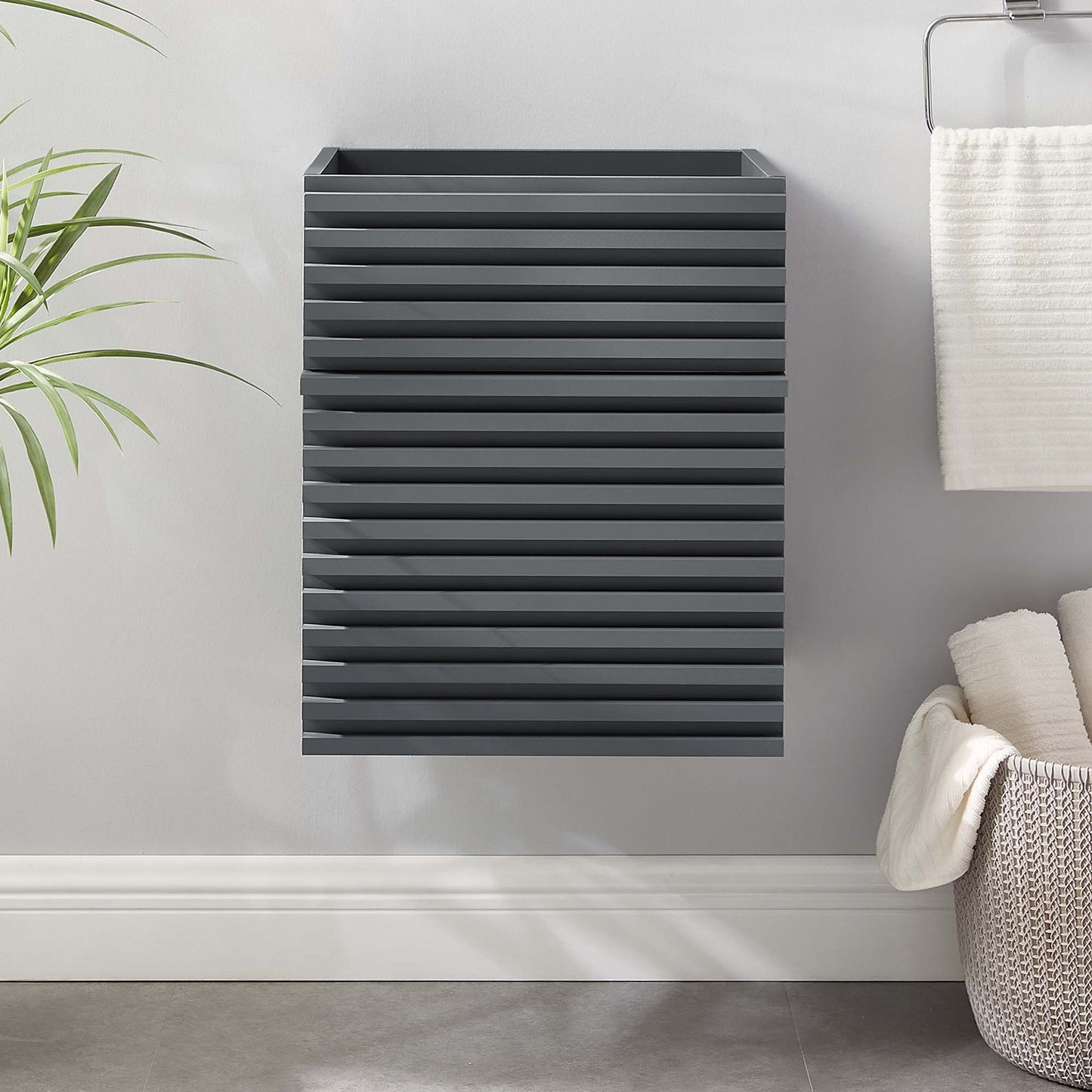 Gray 18-inch wall-mounted bathroom vanity cabinet; sink basin not included, in a modern bathroom scene with a plant and a woven basket.