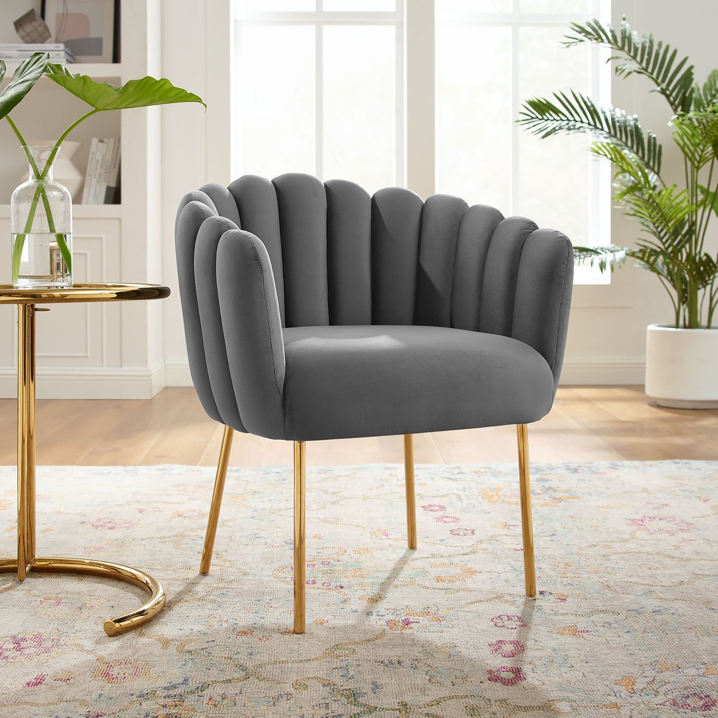 Gray velvet channel-tufted armchair with gold legs in a bright living room.