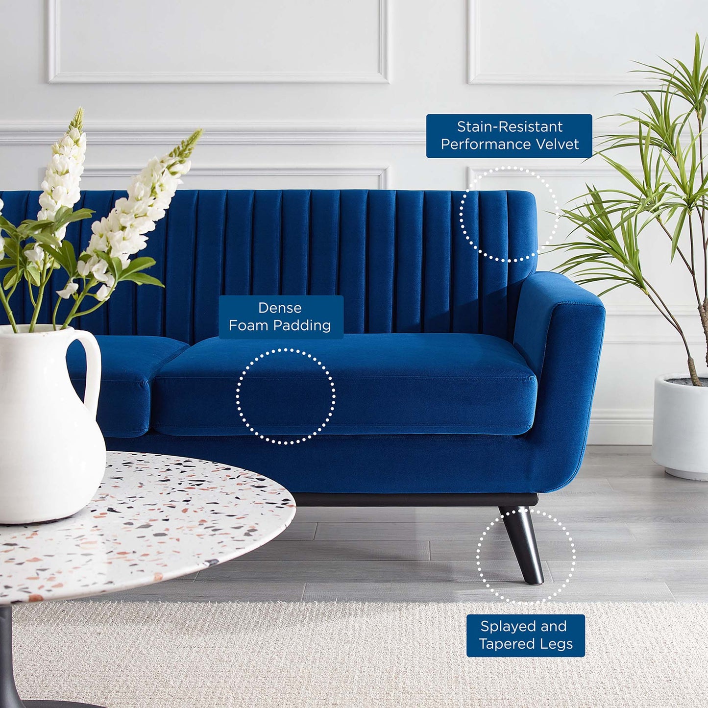 Blue velvet sofa with dense foam padding, stain-resistant performance velvet, and splayed tapered legs in a living room.