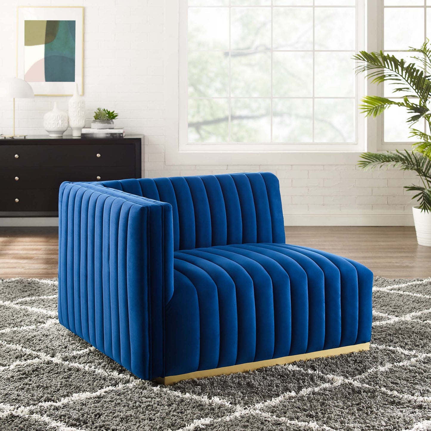 Navy blue velvet channel-tufted left-arm chair with a gold metal base, modern living-room accent.