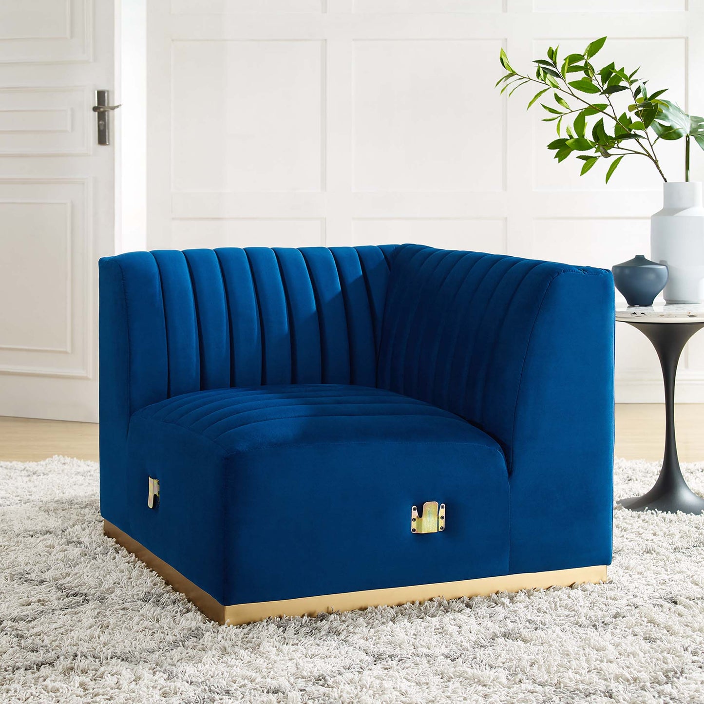 Navy blue velvet curved accent chair with vertical channel tufting, gold-tone base, modern living room lounge.