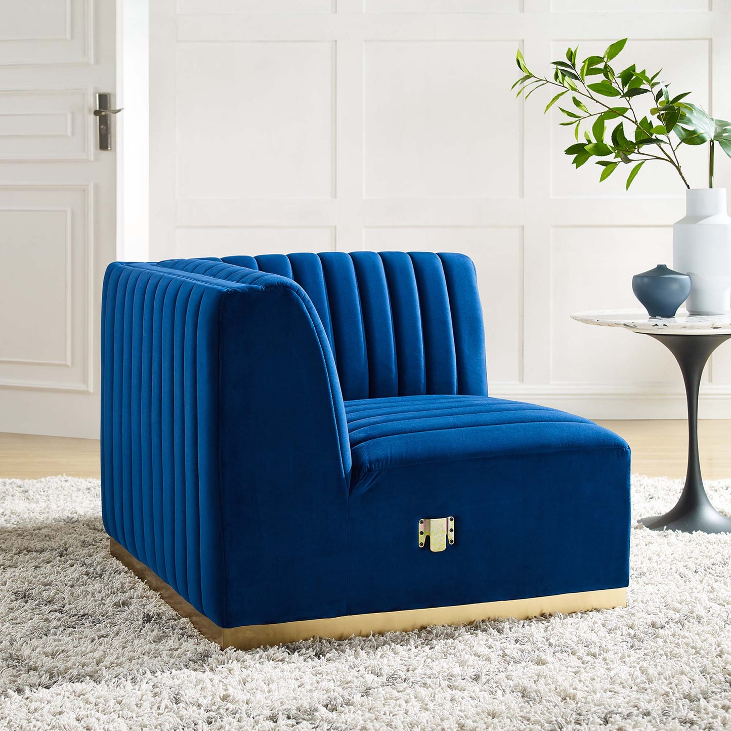 Navy velvet corner chair with vertical channel tufting and a gold base trim for a modern living space.