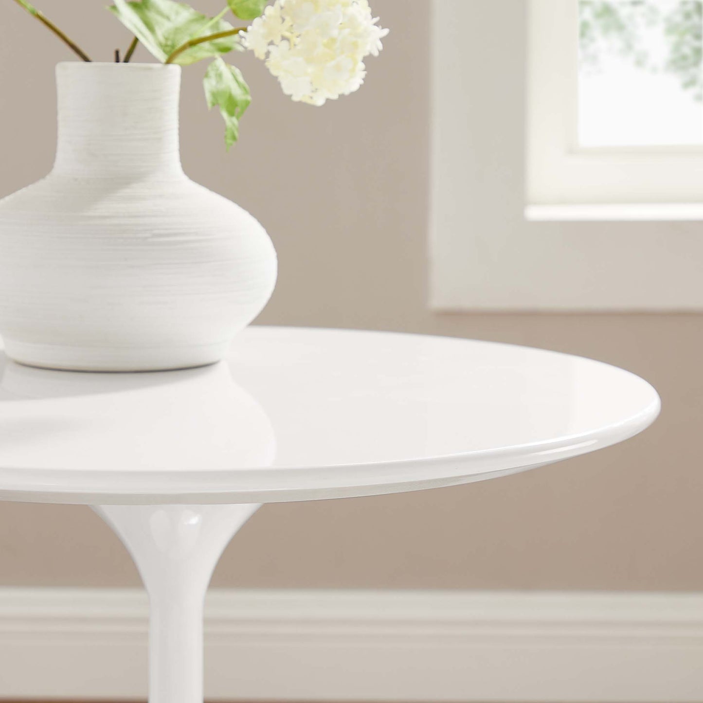 White round wood side table with a glossy finish, featuring a white ceramic vase with pale flowers.