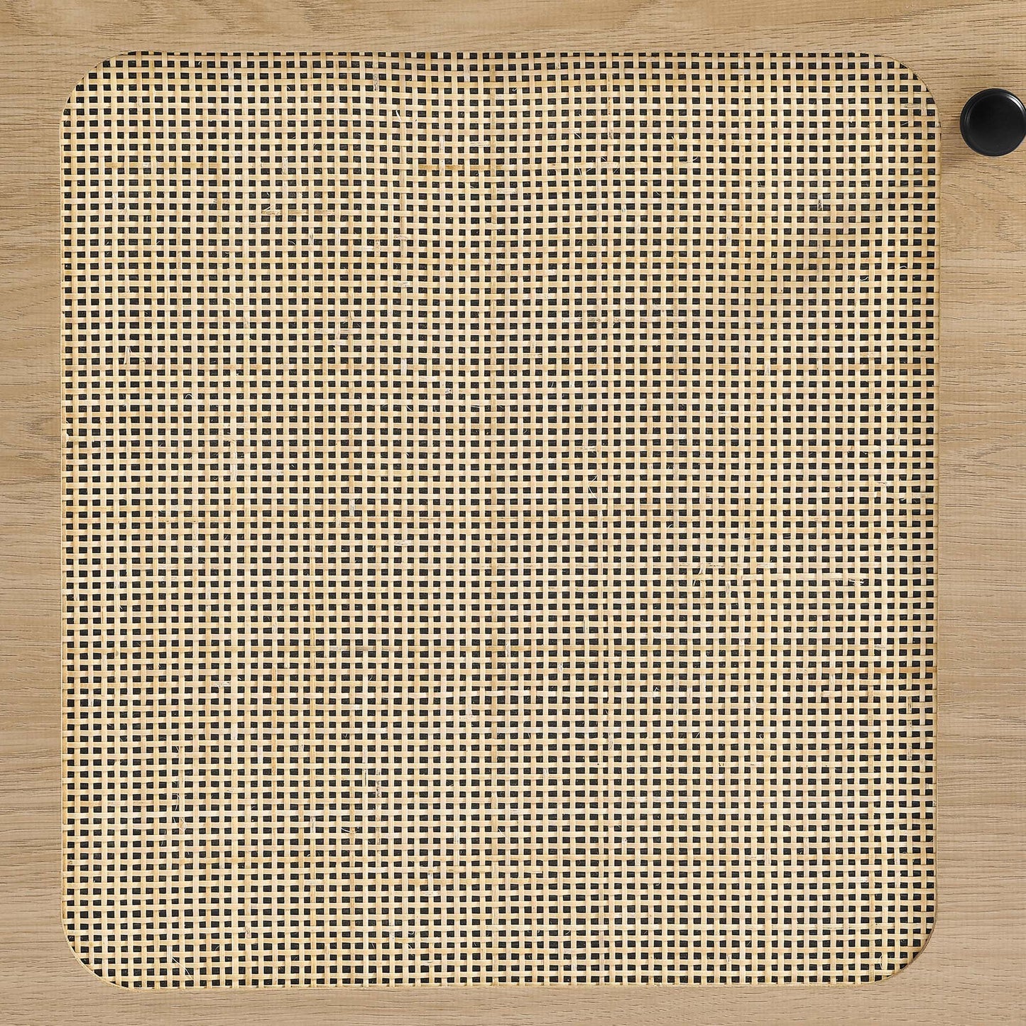 Oak-finish square panel with rounded corners and woven cane grid center; black knob at top-right.